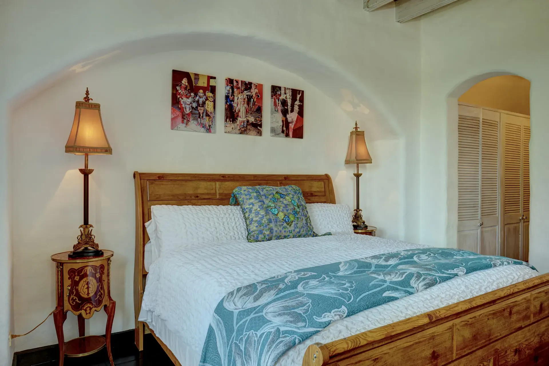 Casa Mi Besito, bedroom with a wood sleigh bed, a teal and white throw and an arched wall with shutters, San Miguel de Allende