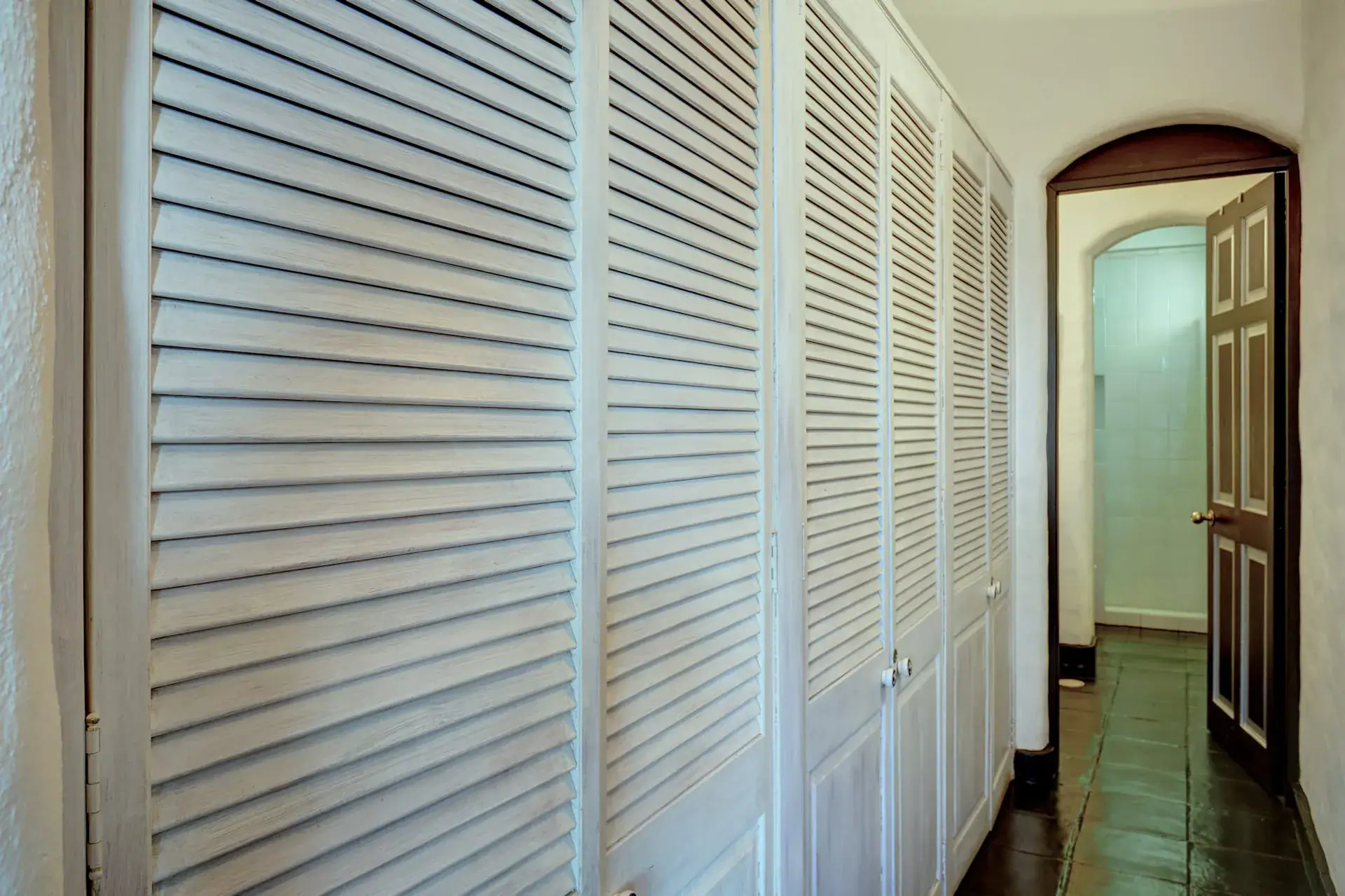 Casa Mi Besito, wall of white louvered closet doors beside an arched doorway, San Miguel de Allende