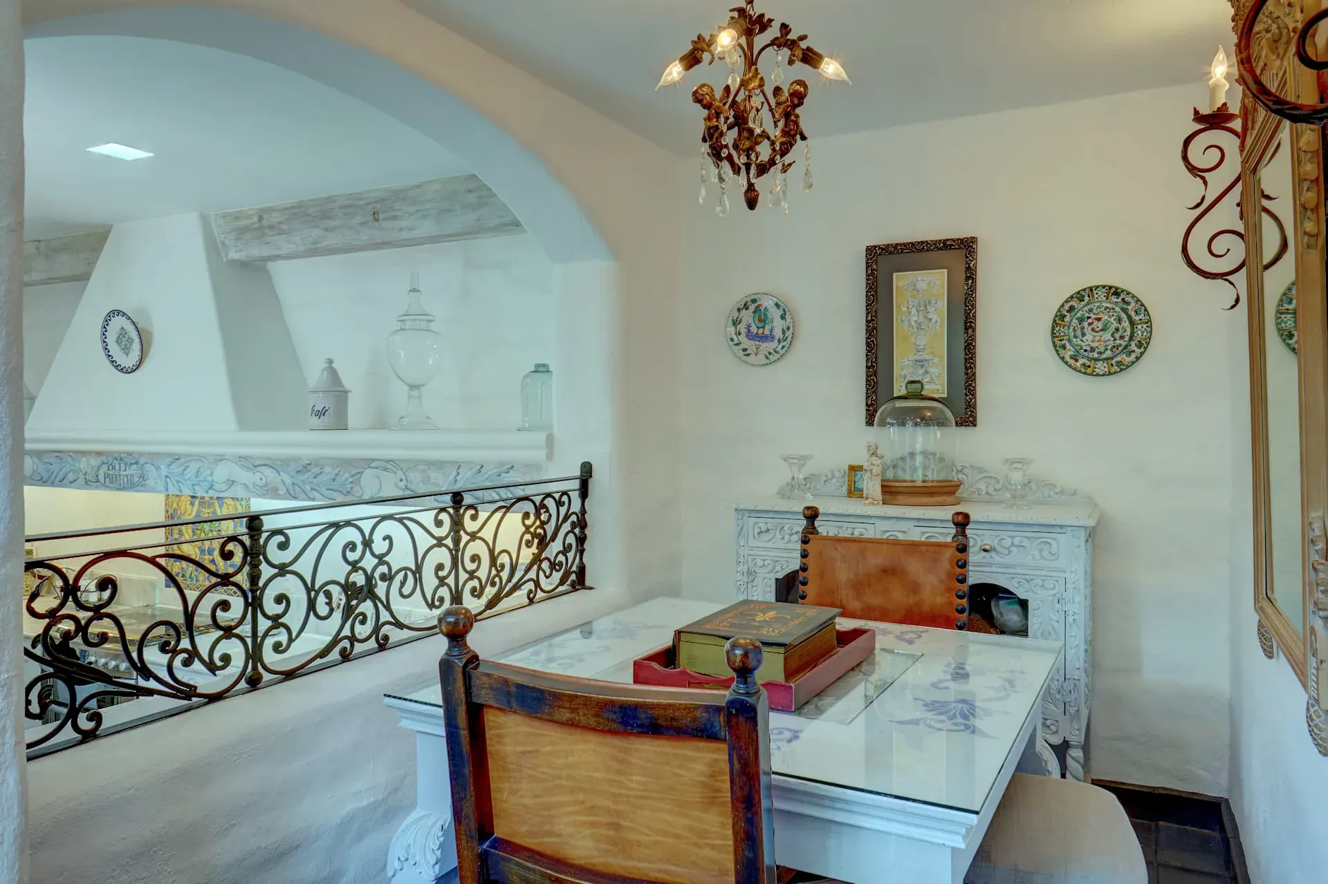 Casa Mi Besito, breakfast nook with a glass table, a scrolled iron railing and plates on the wall, San Miguel de Allende