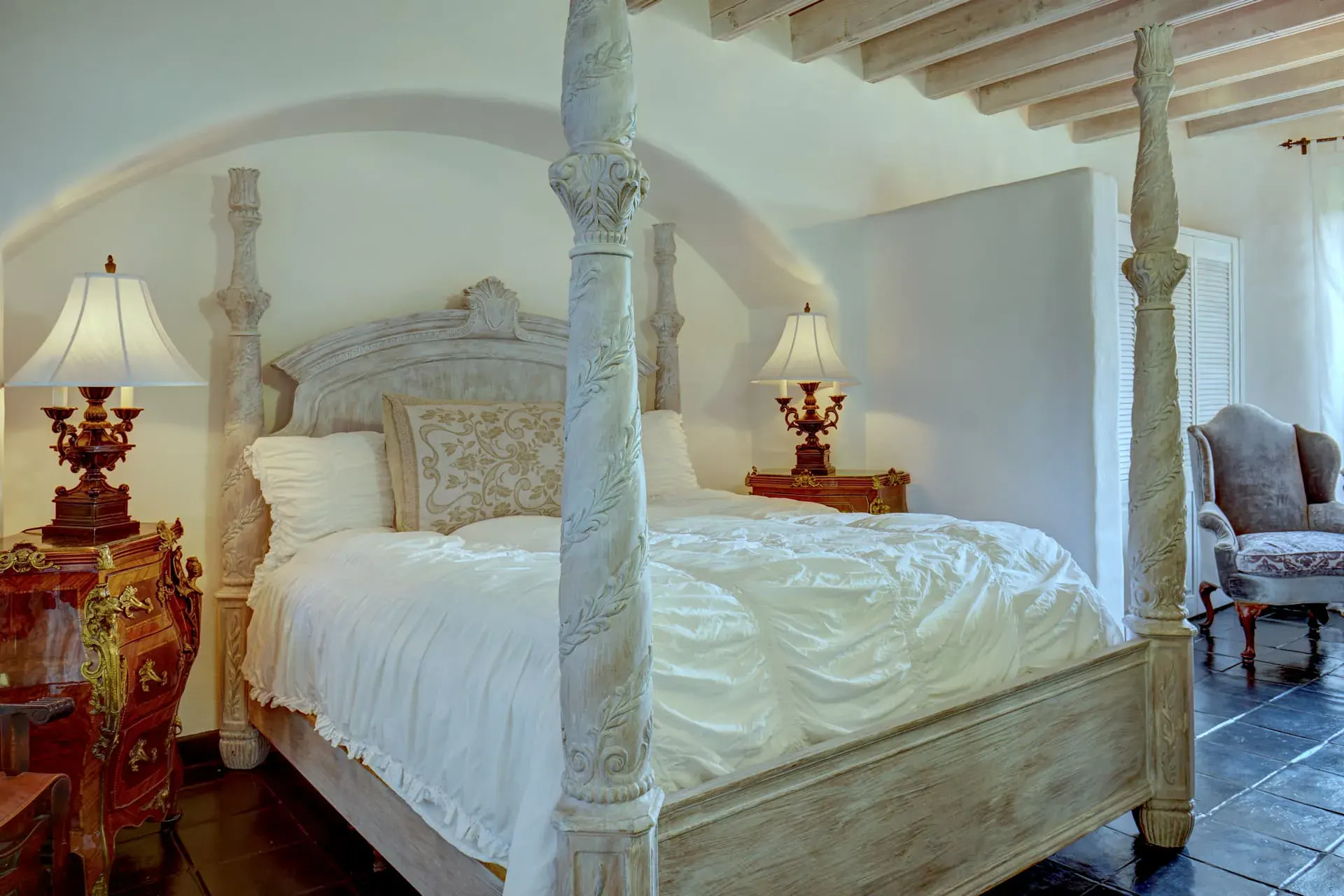 Casa Mi Besito, bedroom with a four-poster bed, a carved nightstand with a lamp and a beamed ceiling, San Miguel de Allende