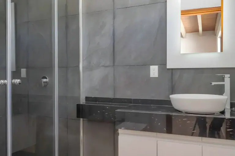 Casa Milagros, bathroom with a gray slate tile shower, a black marble counter and a white vessel sink, San Miguel de Allende