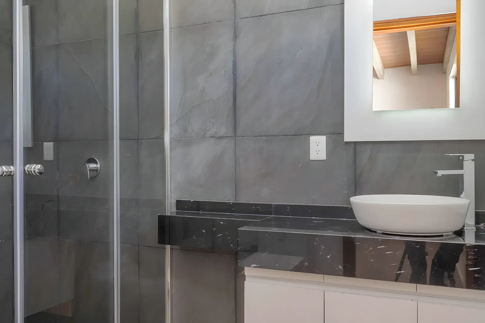 Casa Milagros, bathroom with a gray slate tile shower, a black marble counter and a white vessel sink, San Miguel de Allende