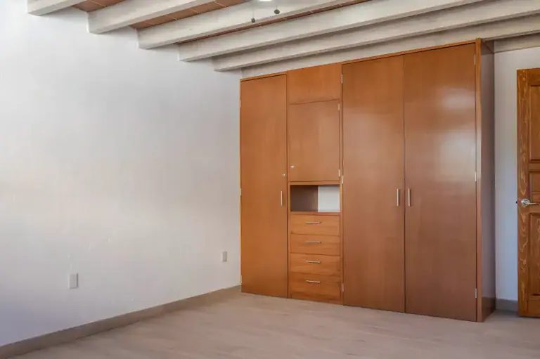 Casa Milagros, empty bedroom with a wood beam ceiling and a built-in wood wardrobe, San Miguel de Allende