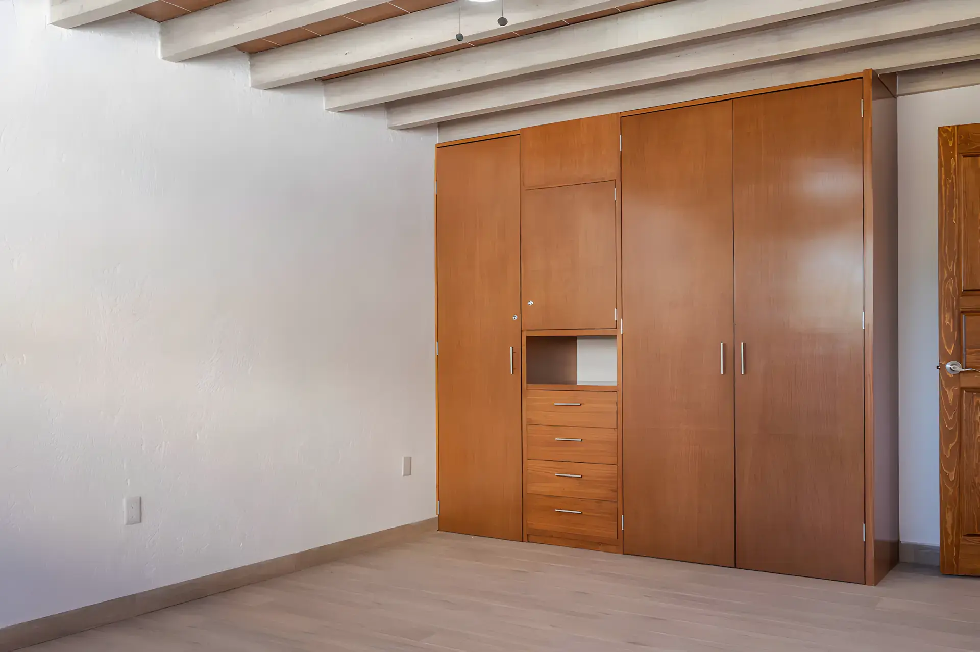 Casa Milagros, empty bedroom with a wood beam ceiling and a built-in wood wardrobe, San Miguel de Allende