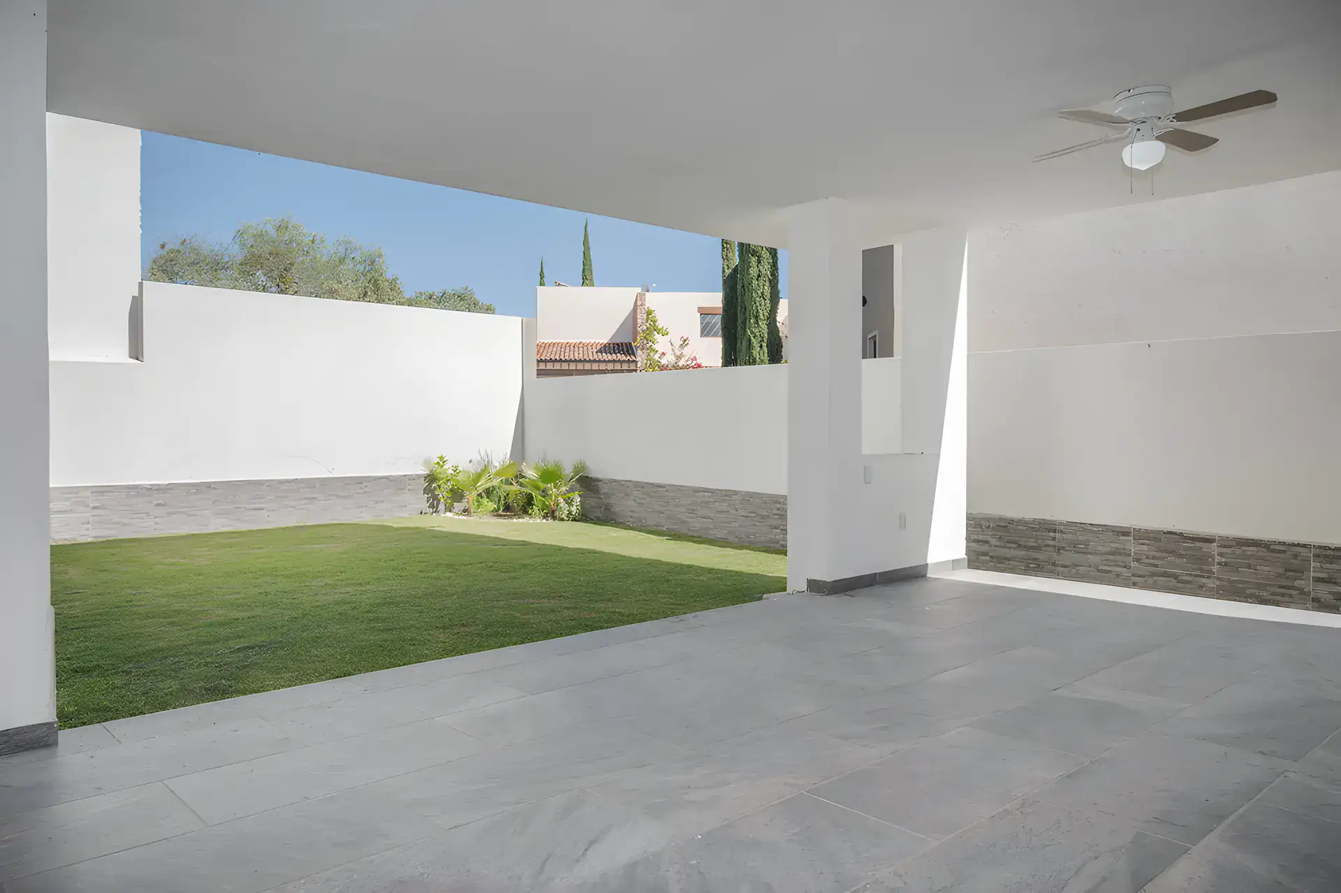 Casa Milagros, covered patio with a slate floor, a ceiling fan and a walled lawn, San Miguel de Allende