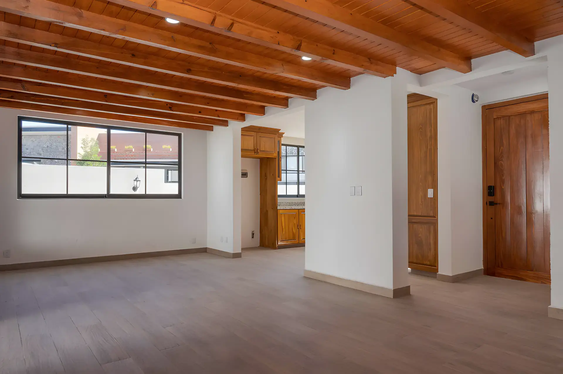 Casa Milagros, empty living and dining area with a wood beam ceiling, a wood front door and a window, San Miguel de Allende