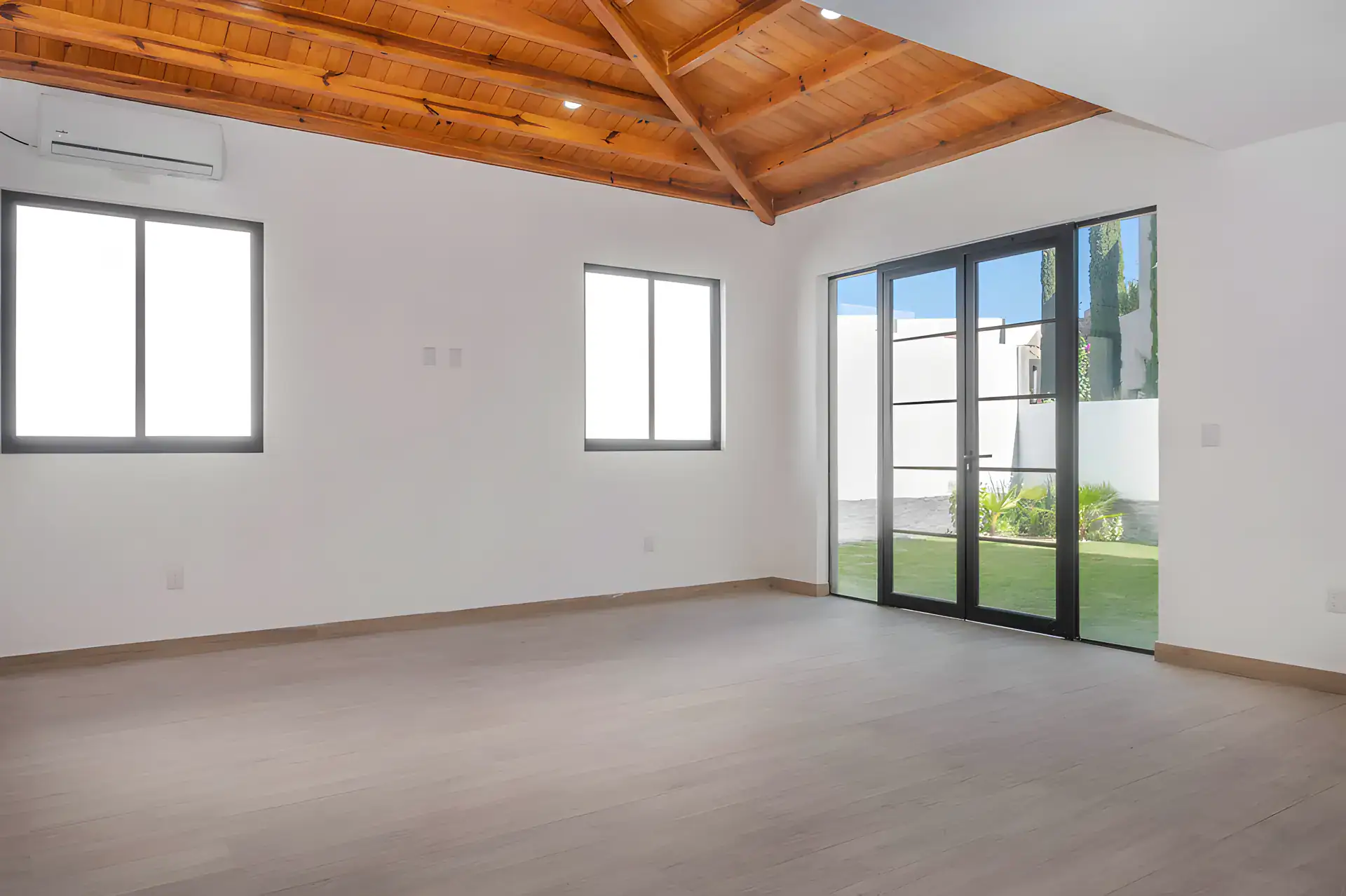 Casa Milagros, empty bedroom with a pitched wood ceiling, a wall air conditioner and glass doors to the garden, San Miguel de Allende