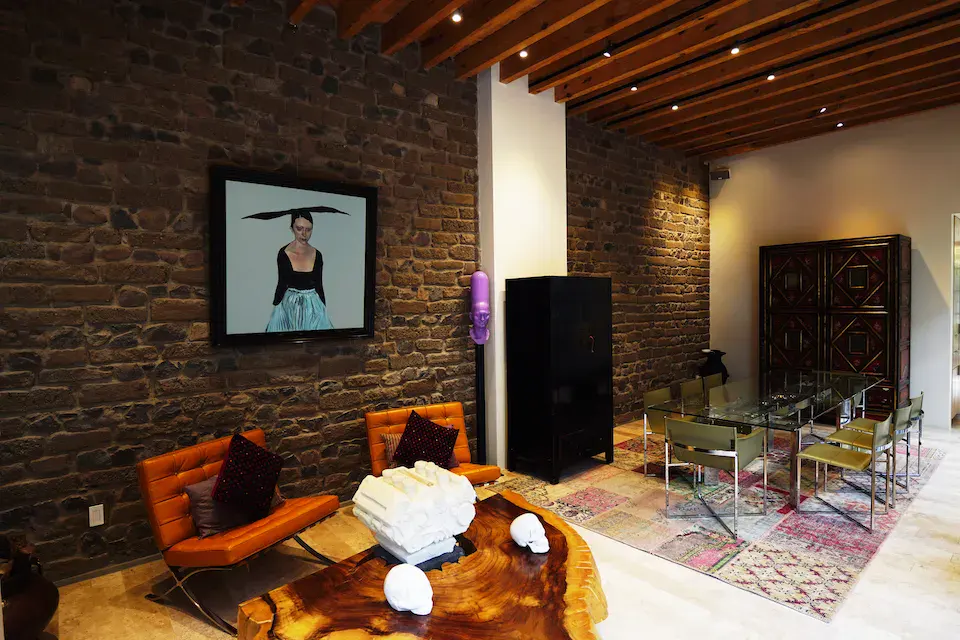 Casa Mojica, dining area with a brick wall, a glass table and a wood beam ceiling, San Miguel de Allende