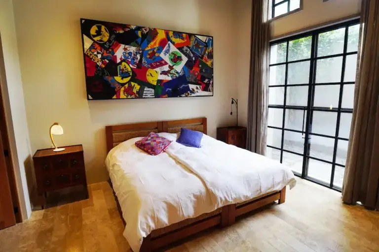 Casa Mojica, bedroom with a large colorful painting and tall steel-framed windows, San Miguel de Allende