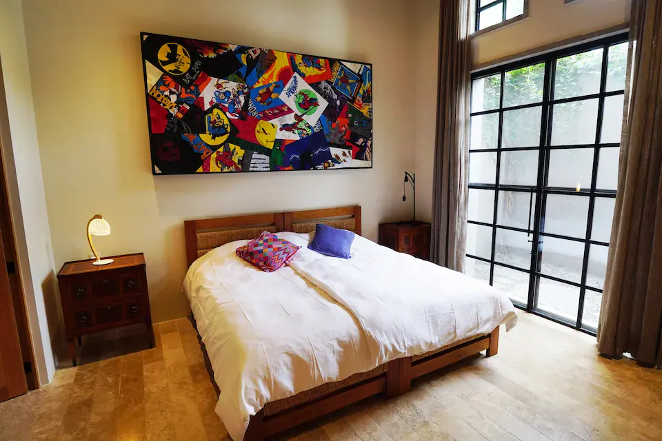 Casa Mojica, bedroom with a large colorful painting and tall steel-framed windows, San Miguel de Allende