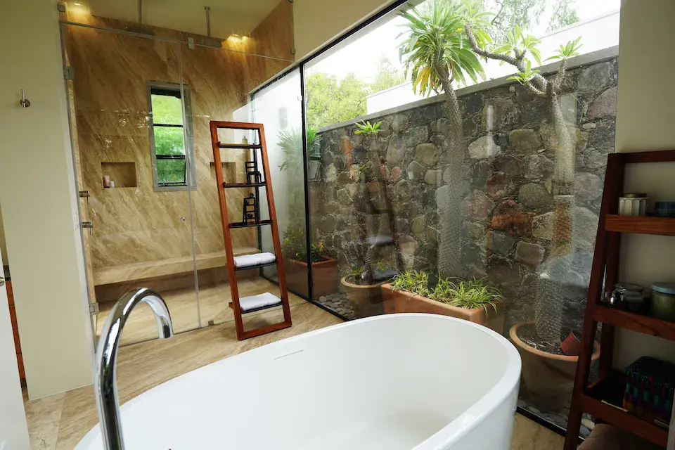 Casa Mojica, bathroom with a freestanding tub and a glass wall facing a stone garden, San Miguel de Allende