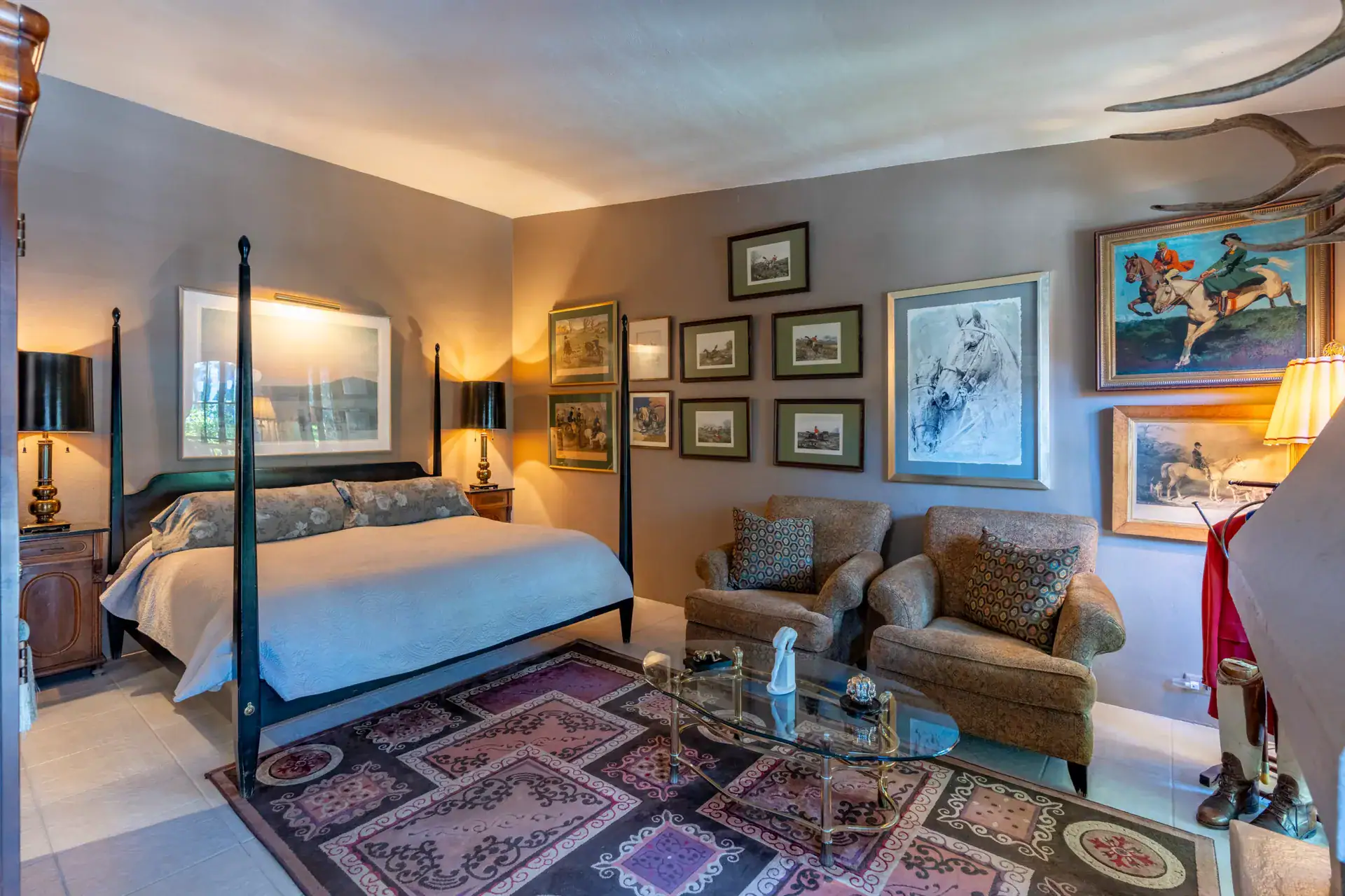 Casa Nispero, bedroom with a four-poster bed, a seating area, a Persian rug and walls covered in framed art, San Miguel de Allende