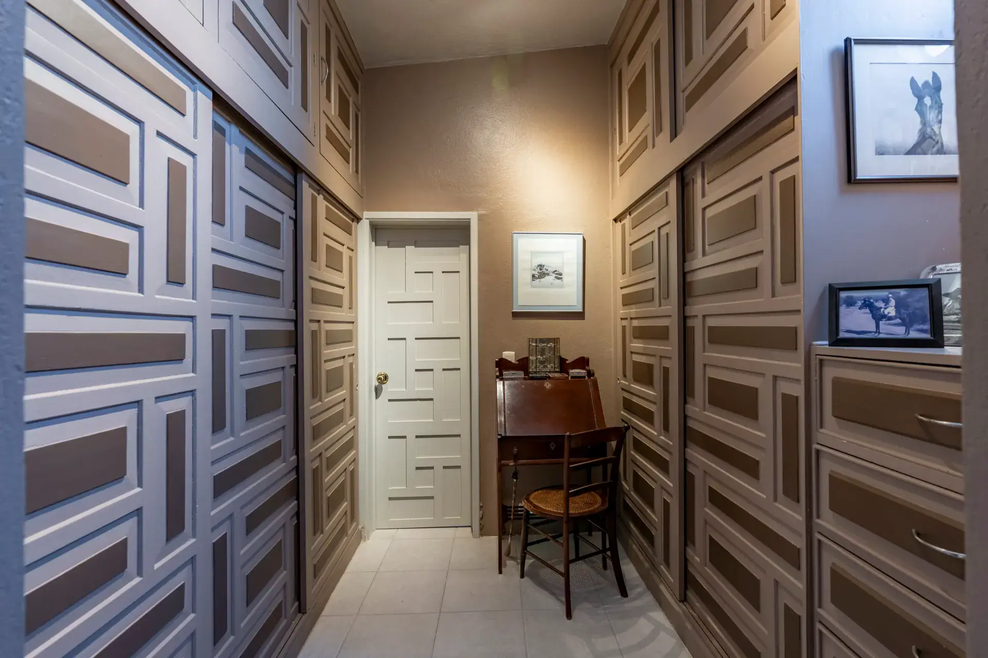 Casa Nispero, dressing room with gray paneled wardrobe doors, a white door and a small writing desk, San Miguel de Allende