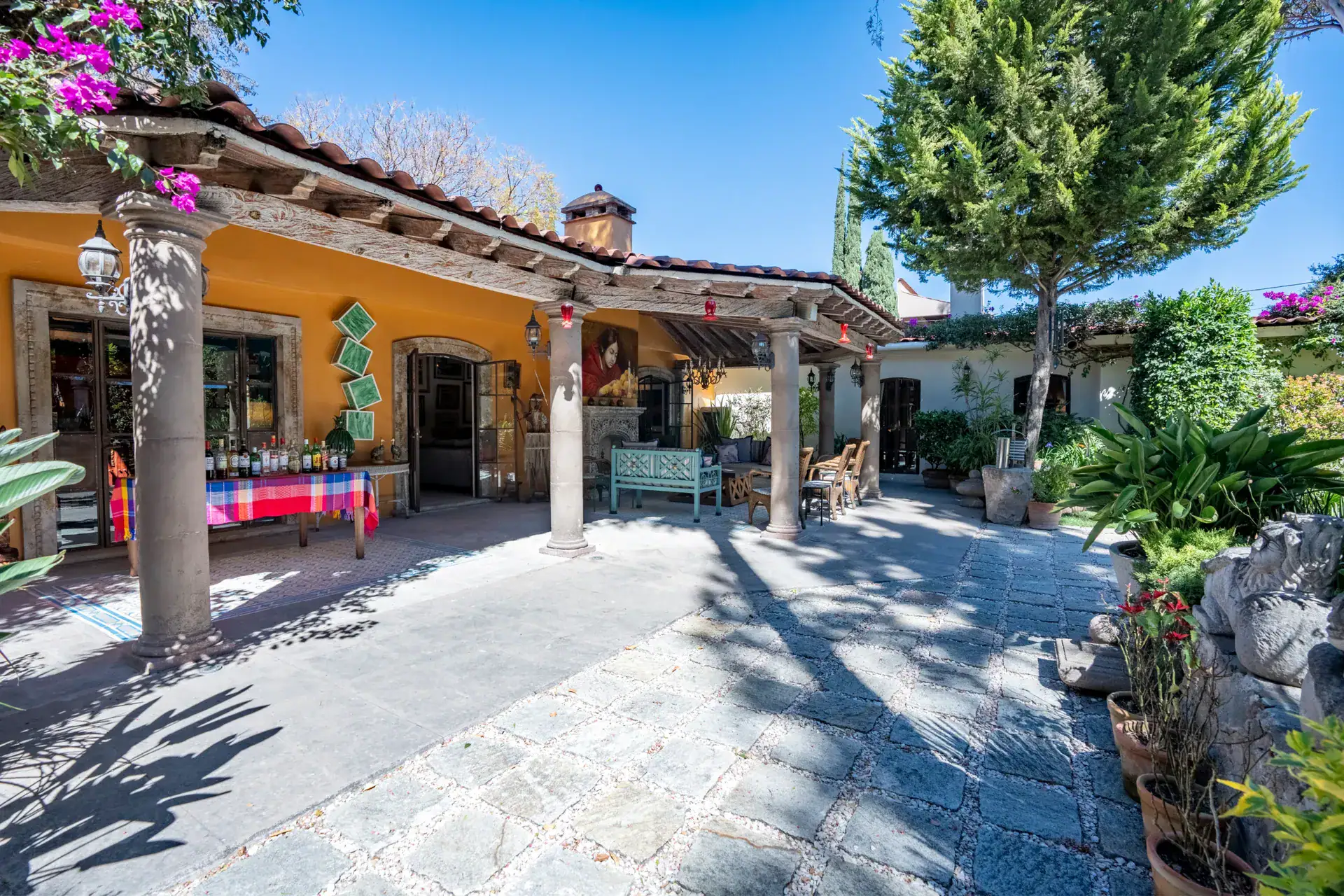 Casa Nispero, covered veranda with stone columns and a beamed roof across a paved courtyard, San Miguel de Allende