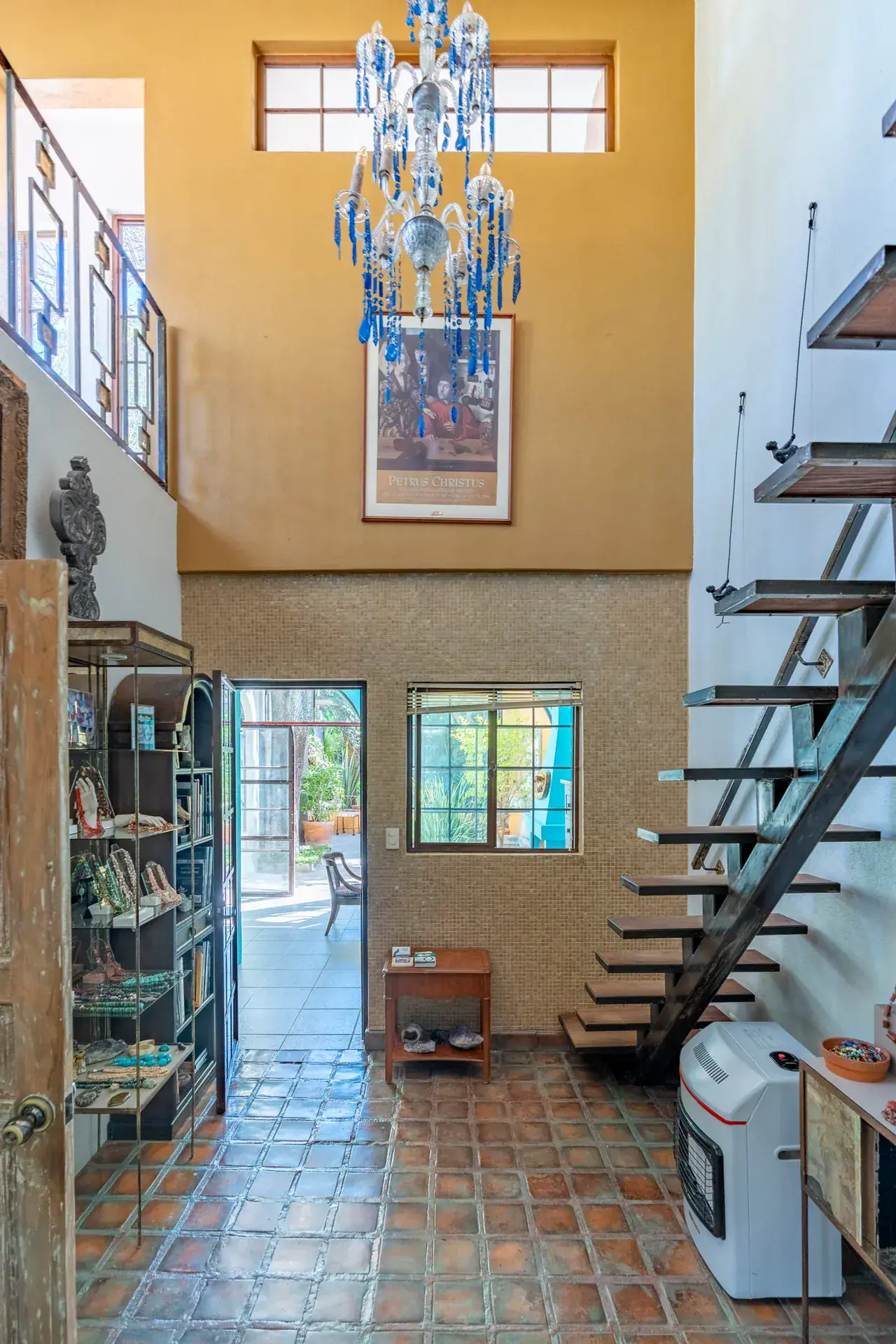 Casa Nispero, double-height room with a modern stair, a crystal chandelier and a glass display cabinet, San Miguel de Allende