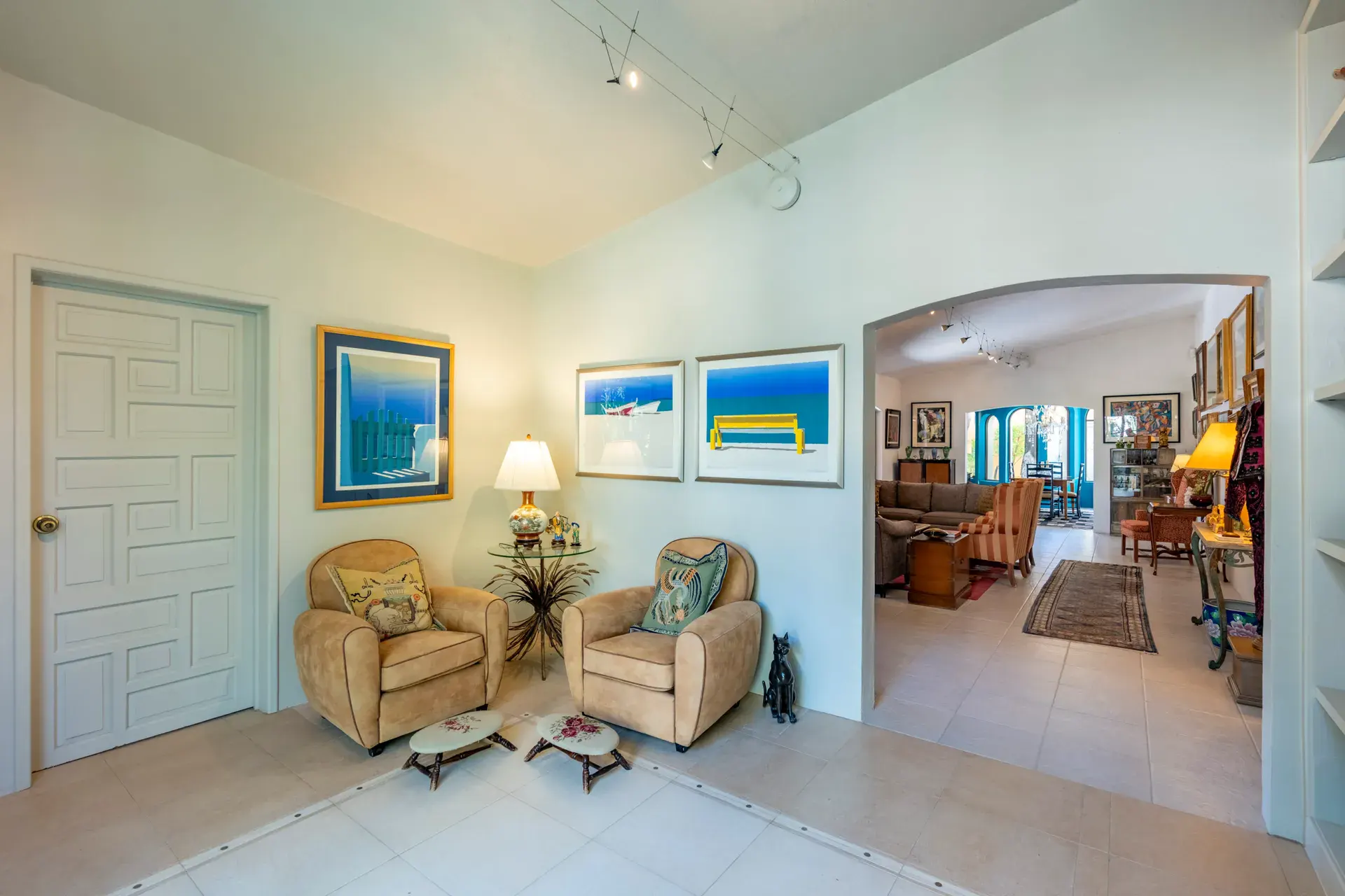 Casa Nispero, foyer sitting area with two armchairs, a white paneled door and framed prints, San Miguel de Allende