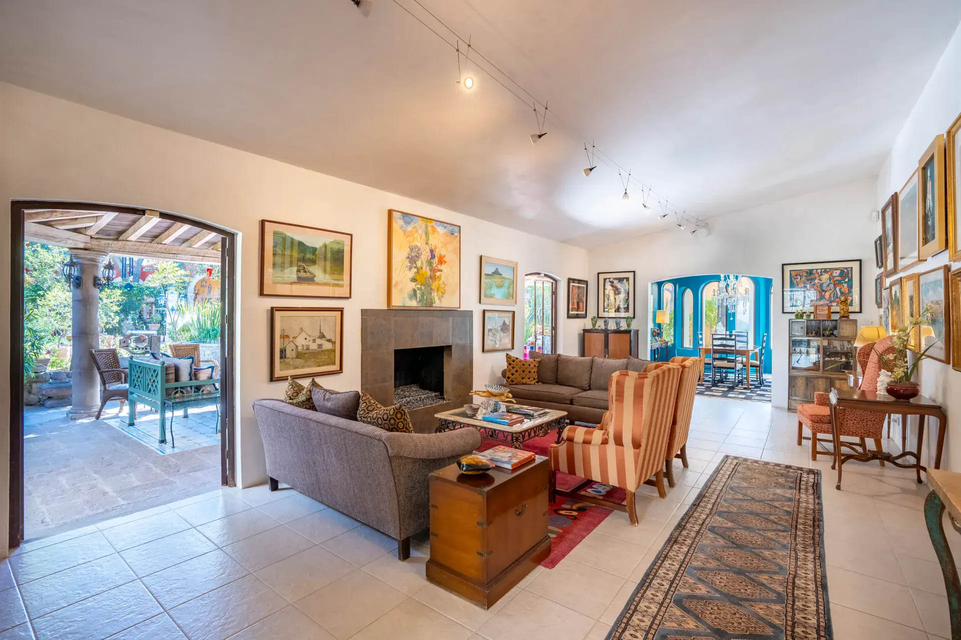 Casa Nispero, living room with a gray sofa, striped wingback chairs, a fireplace and a view to the veranda, San Miguel de Allende