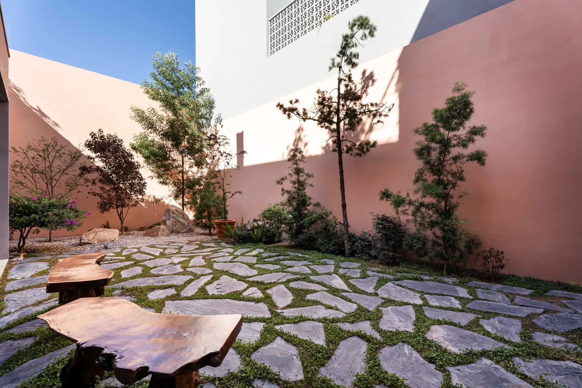 Casa Nobel, garden courtyard with irregular flagstone paving and live-edge wood benches, San Miguel de Allende