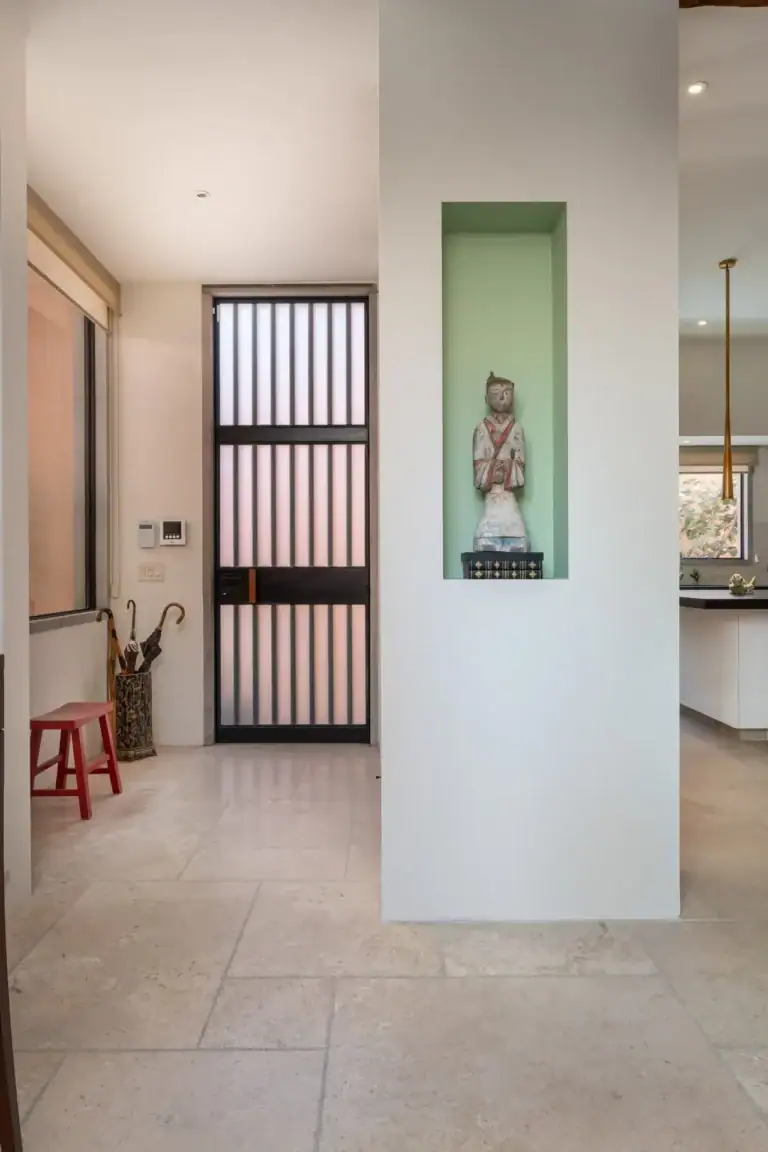 Casa Nobel, entry hall with a black grille door, a green niche with a statue and a view to the kitchen, San Miguel de Allende
