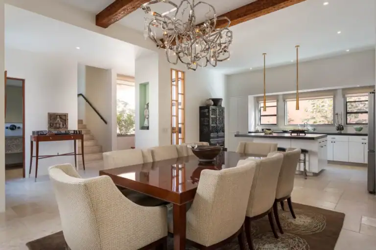 Casa Nobel, dining area with a polished wood table, cream chairs, a sculptural chandelier and a view to the kitchen, San Miguel de Allende