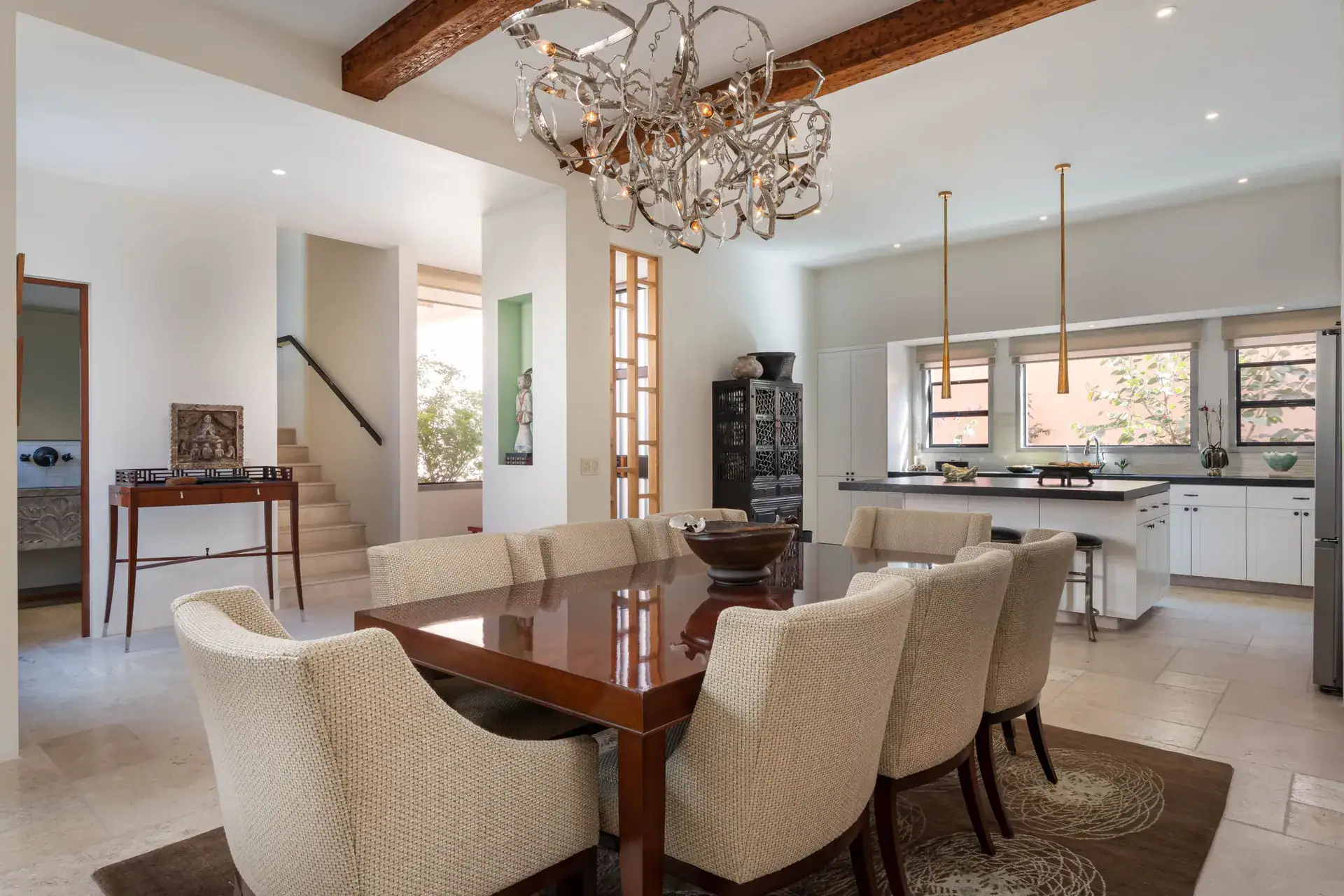 Casa Nobel, dining area with a polished wood table, cream chairs, a sculptural chandelier and a view to the kitchen, San Miguel de Allende