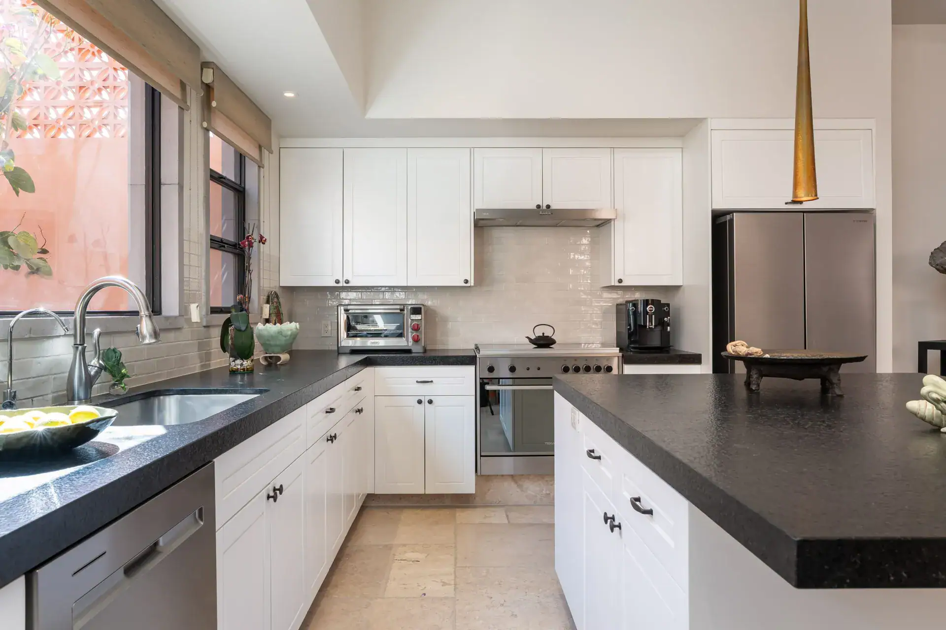 Casa Nobel, kitchen with white cabinets, black counters, a gold pendant light and a steel range, San Miguel de Allende