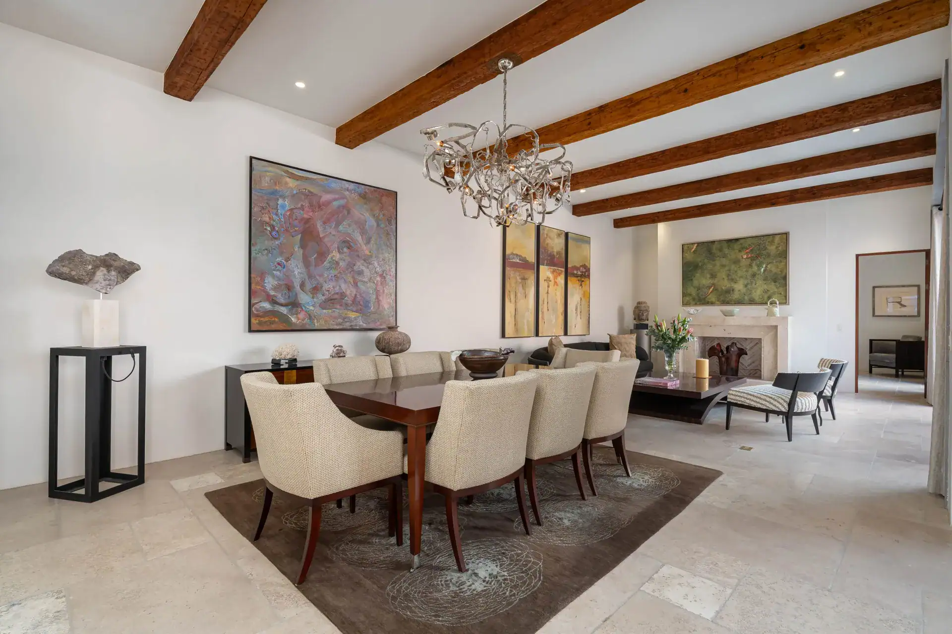Casa Nobel, dining room with a polished table, a sculpture on a stand and a fireplace beyond, San Miguel de Allende