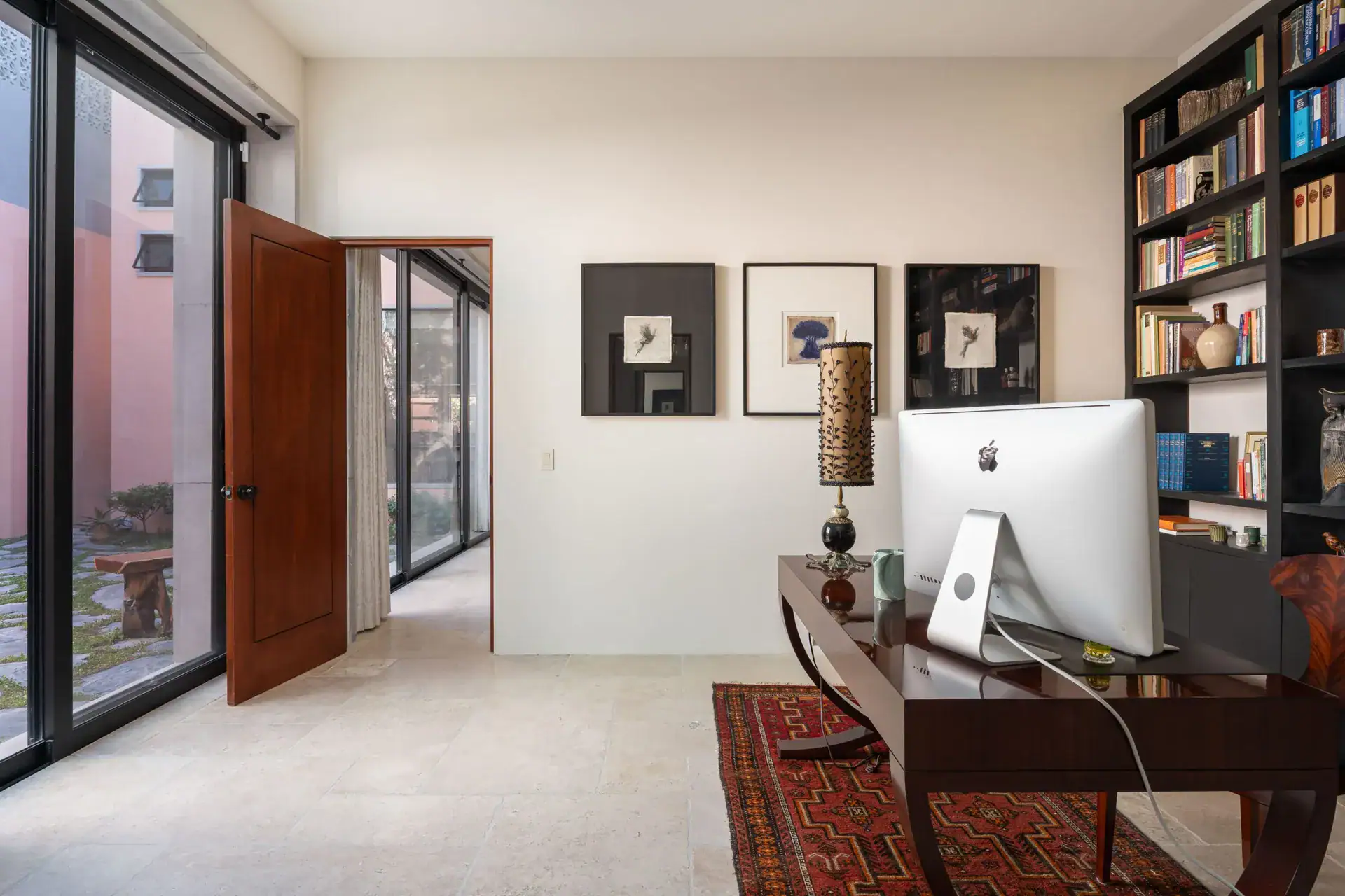 Casa Nobel, study with a desk, a computer and a black bookcase beside a glass door, San Miguel de Allende