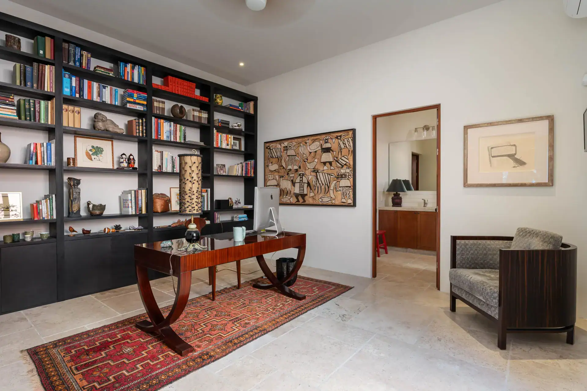 Casa Nobel, study with a wall of books, a curved wood desk and a red patterned rug, San Miguel de Allende