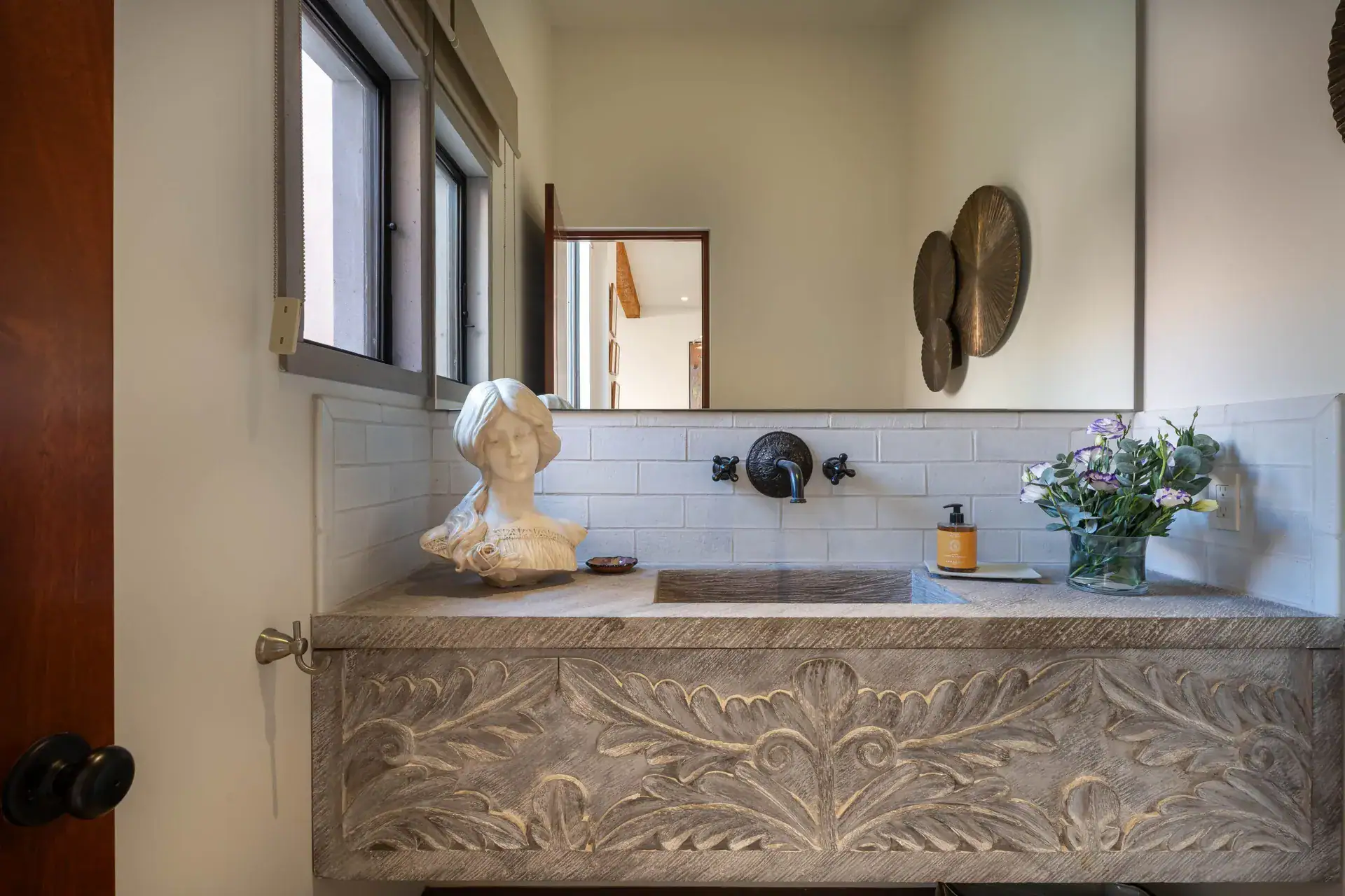 Casa Nobel, powder room with a carved stone vanity, a marble bust and a white tile backsplash, San Miguel de Allende
