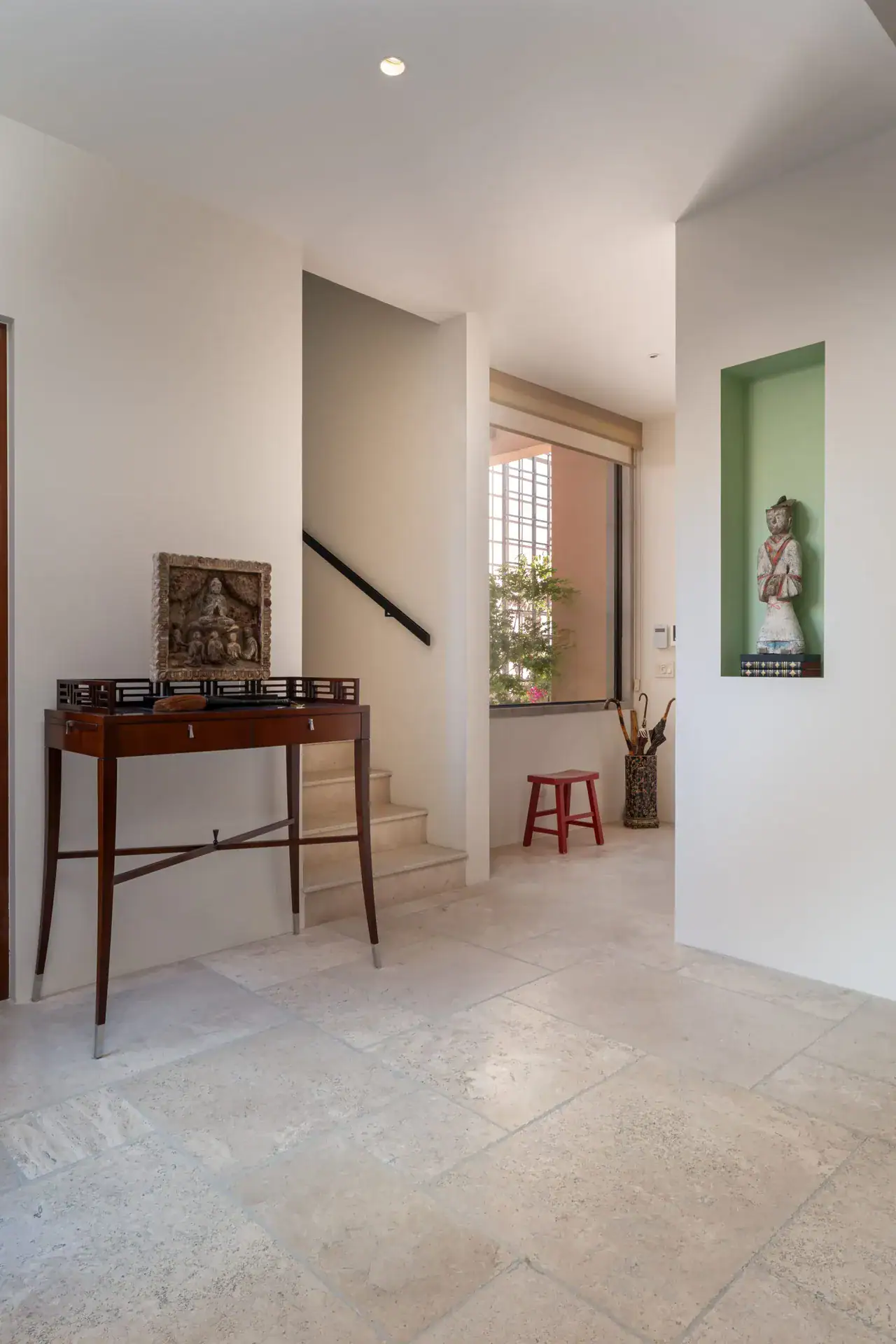 Casa Nobel, stairs landing with a console table, a statue niche and a window screen, San Miguel de Allende