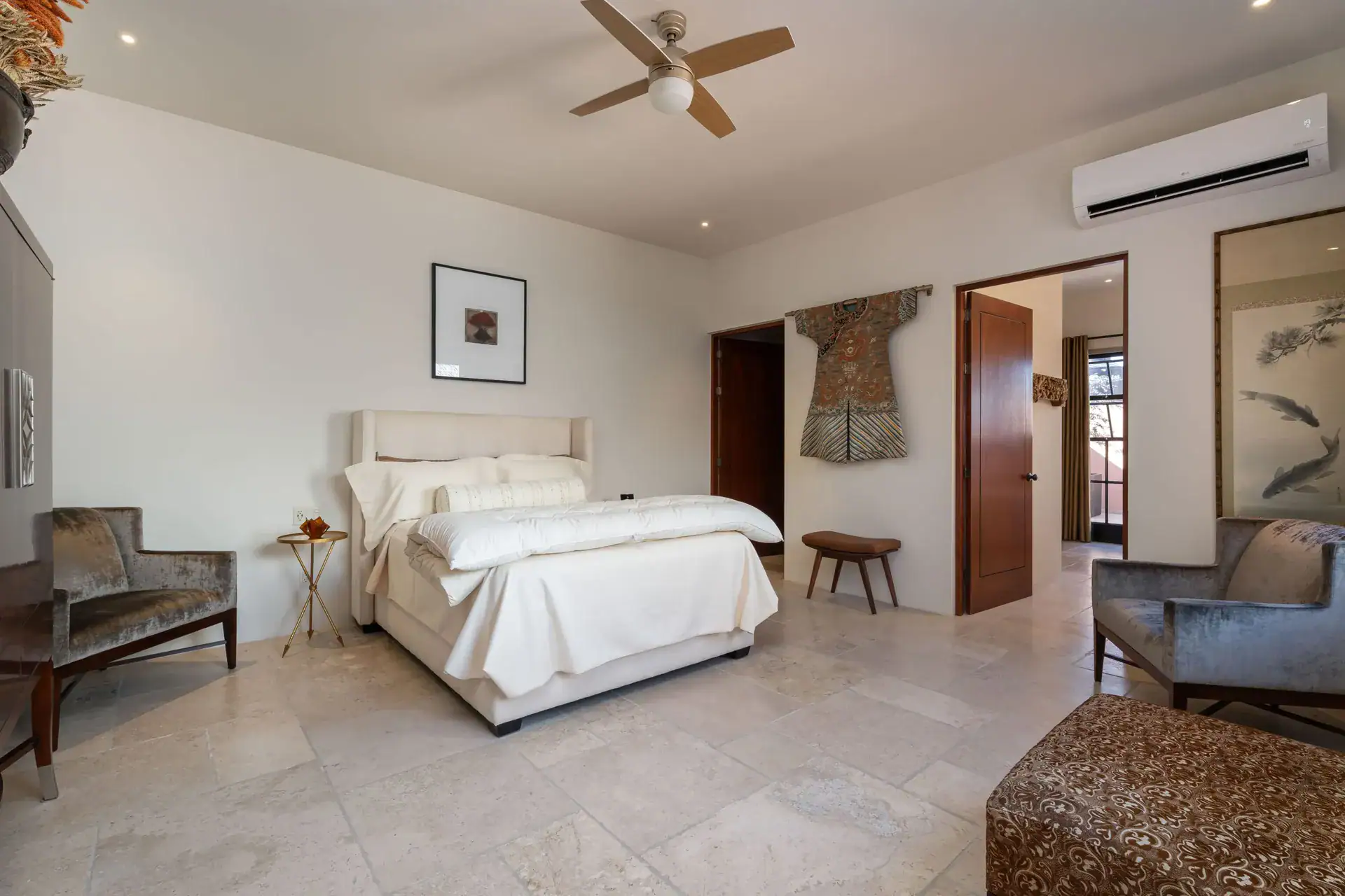 Casa Nobel, bedroom with a cream headboard, gray velvet chairs and a ceiling fan, San Miguel de Allende