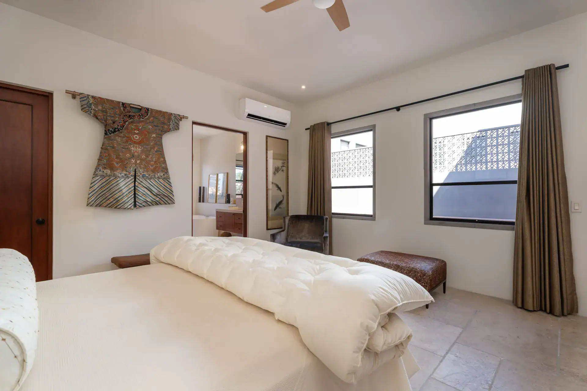 Casa Nobel, bedroom with a framed silk robe on the wall, a cream duvet and curtains, San Miguel de Allende