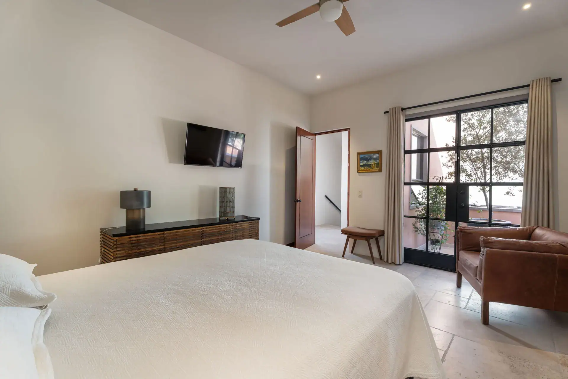 Casa Nobel, bedroom with a wall-mounted television, a leather armchair and glass doors to a balcony, San Miguel de Allende