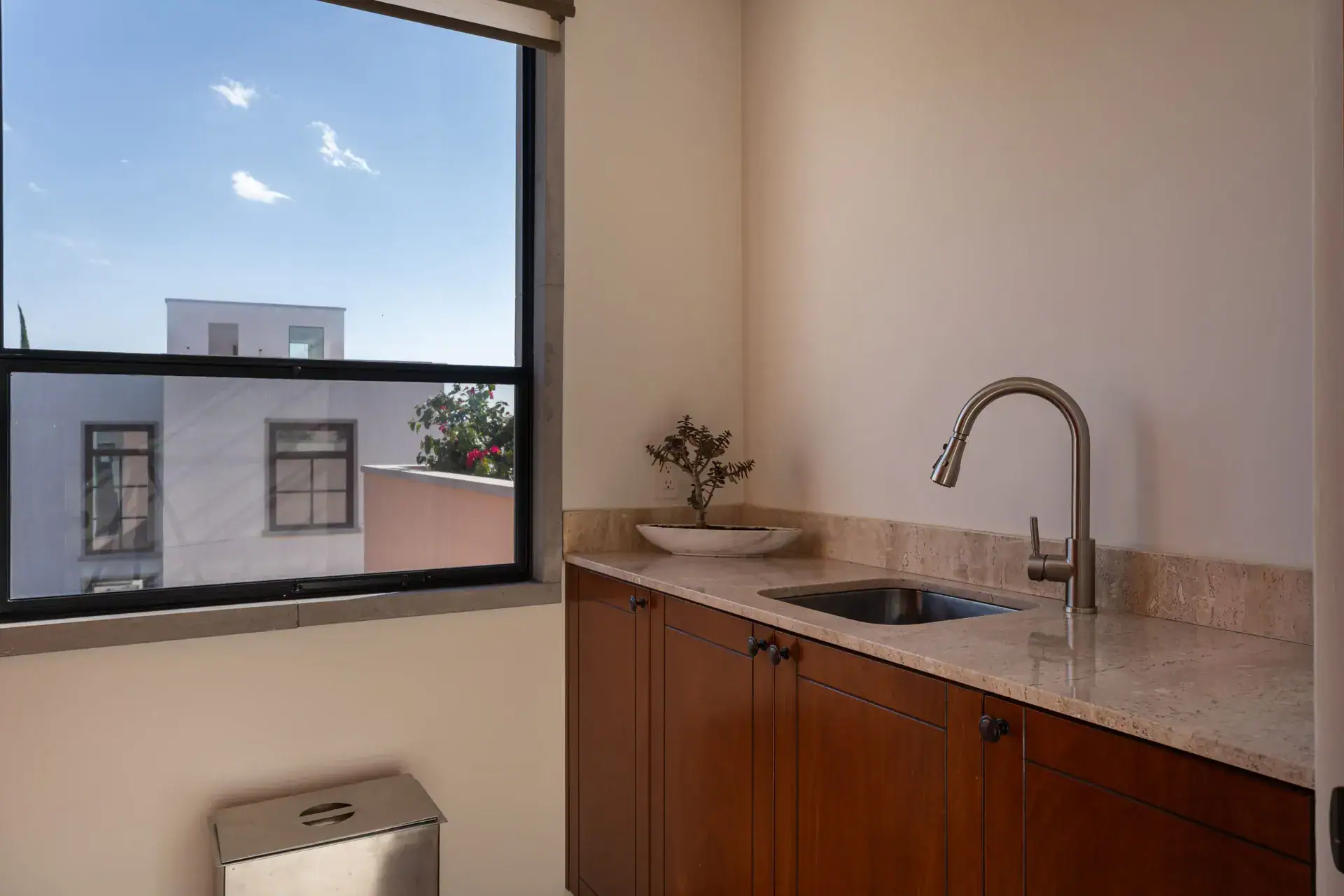 Casa Nobel, small room with a sink, a wood cabinet and a window onto the neighboring roofs, San Miguel de Allende
