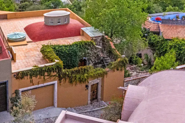Casa Noche Magica, aerial view of the house's terracotta roof terraces with a pink dome and ivy-covered walls, San Miguel de Allende