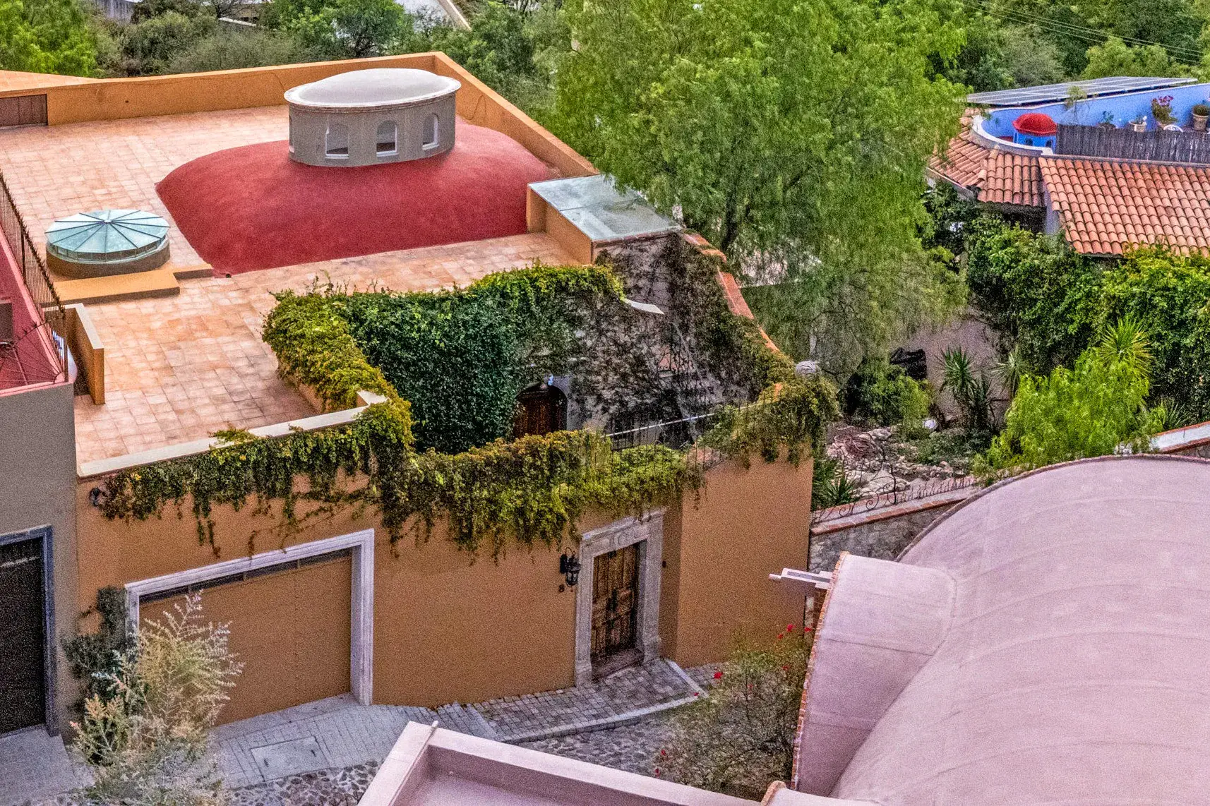 Casa Noche Magica, aerial view of the house's terracotta roof terraces with a pink dome and ivy-covered walls, San Miguel de Allende