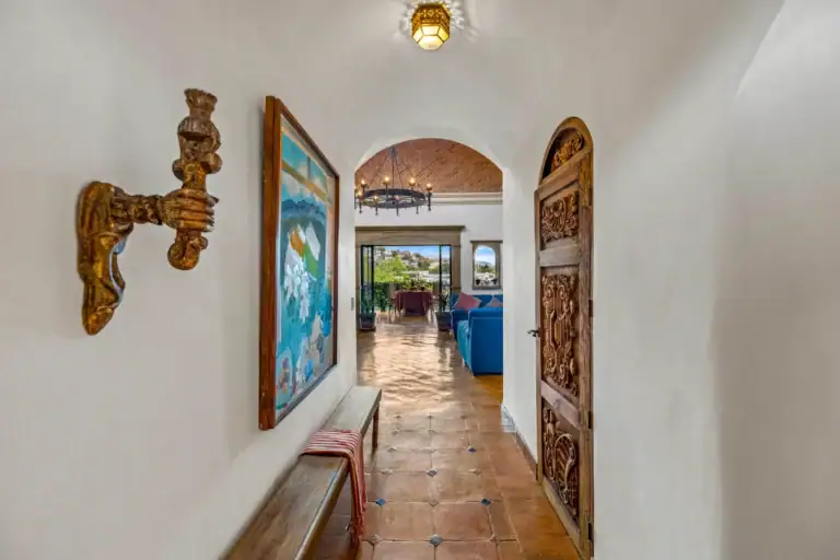 Casa Noche Magica, entry hallway with a carved wood door, a framed painting and a view to the living room, San Miguel de Allende