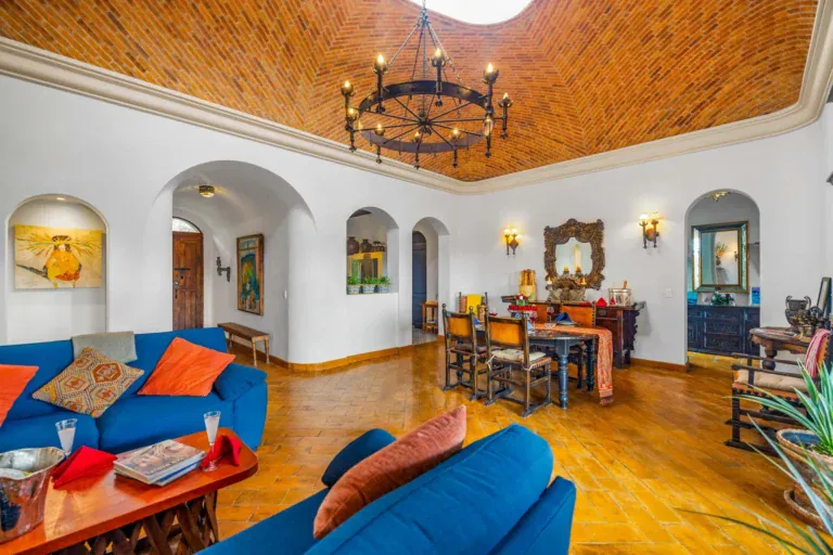 Casa Noche Magica, living room with blue sofas, orange pillows and a dining area under a brick vaulted ceiling, San Miguel de Allende