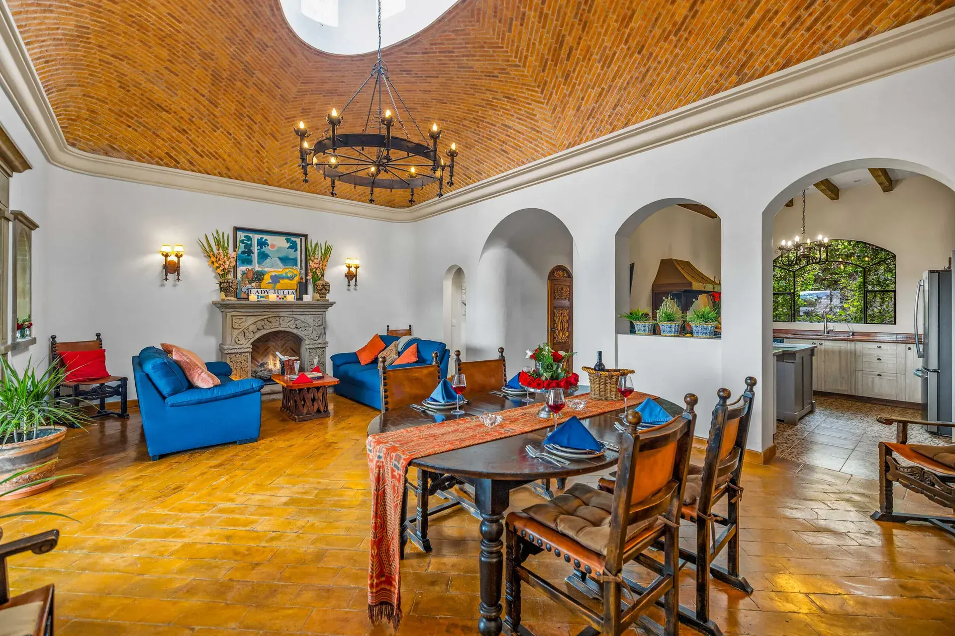 Casa Noche Magica, dining room with a long table and a view to the living room fireplace and a kitchen arch, San Miguel de Allende