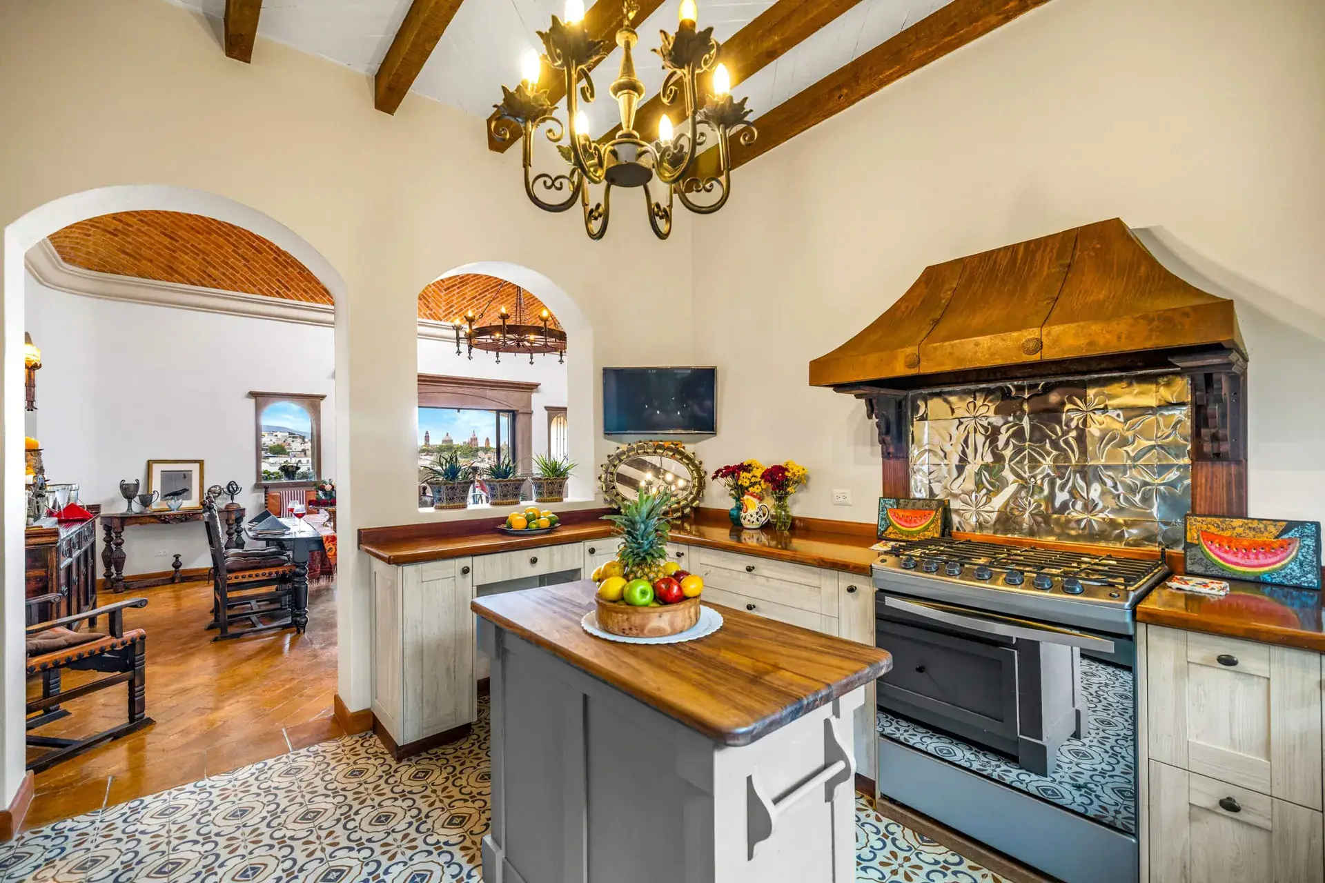 Casa Noche Magica, kitchen with an arched passage, a stainless range, a hammered copper hood and a wood island, San Miguel de Allende