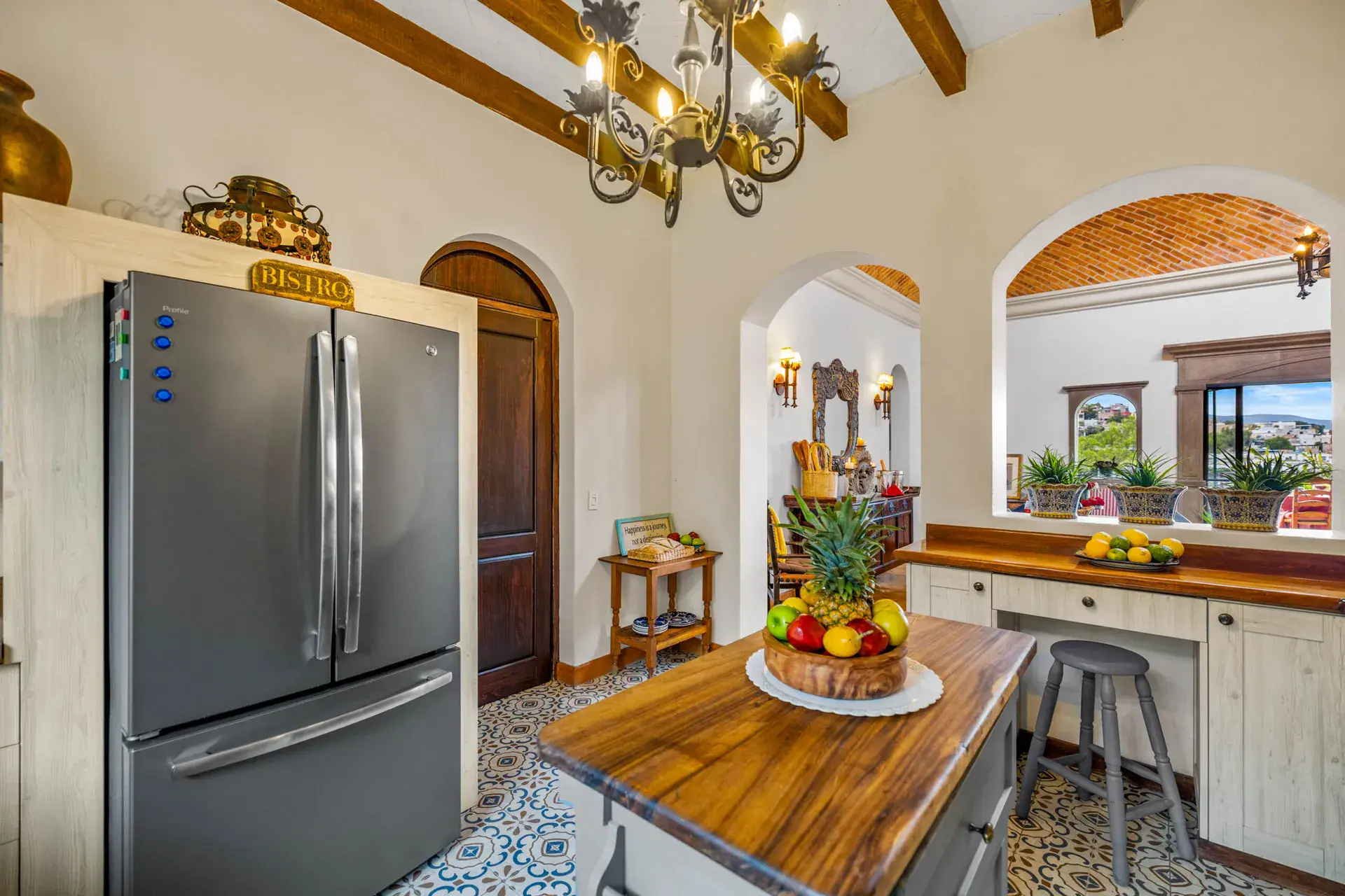 Casa Noche Magica, kitchen with a stainless refrigerator, wood and gray island and an arched wood door, San Miguel de Allende
