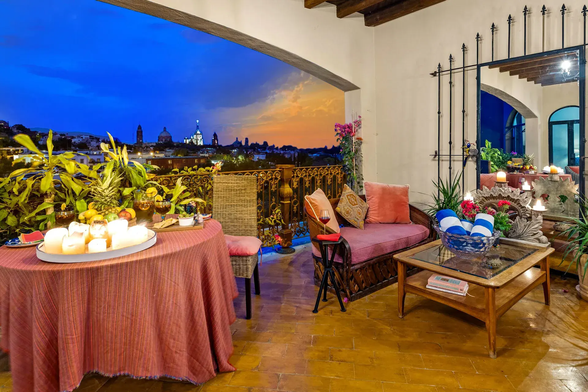 Casa Noche Magica, terrace at dusk with a candlelit table, a daybed and a view of the glowing town, San Miguel de Allende