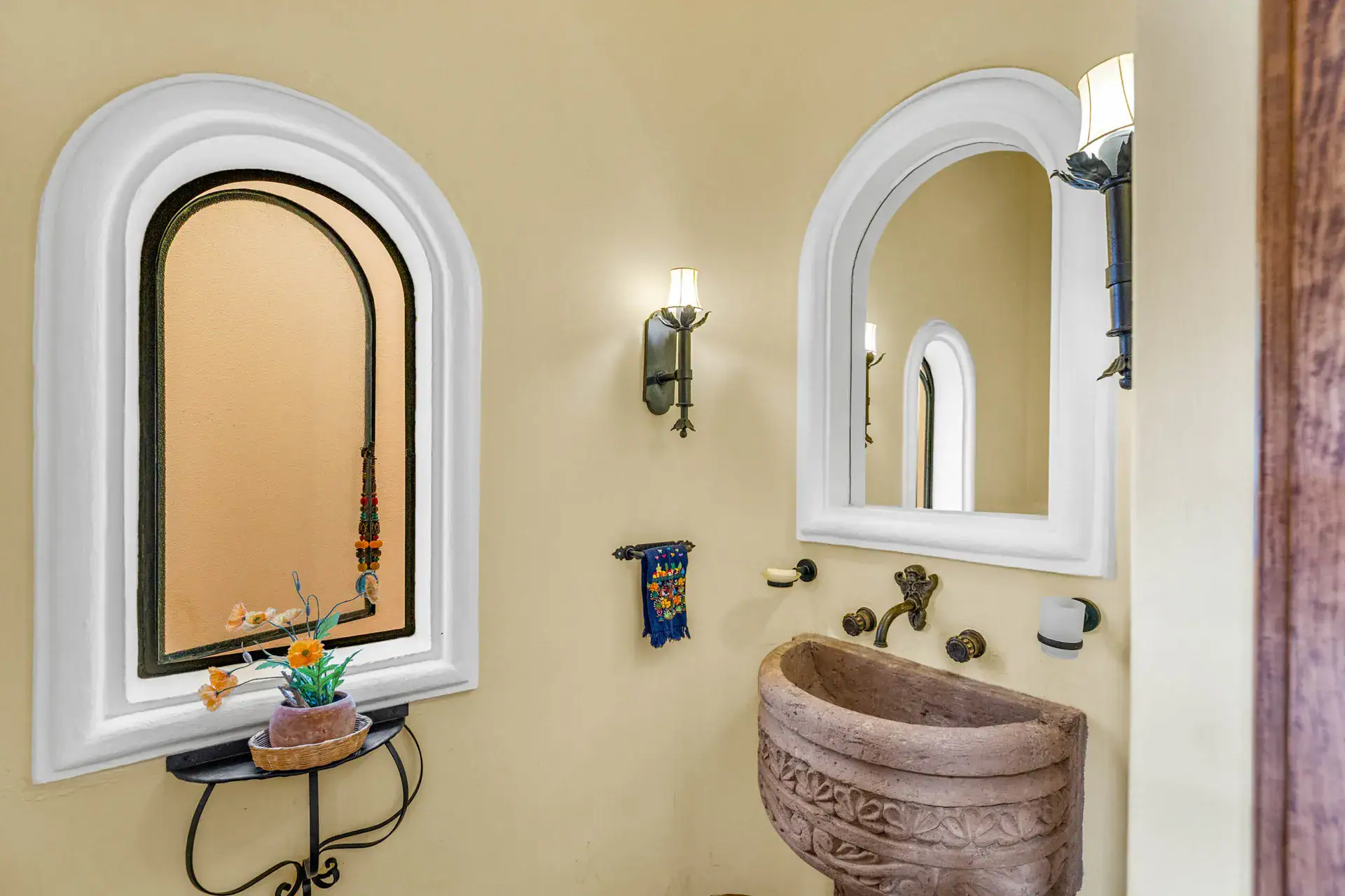Casa Noche Magica, powder room with arched windows, a carved stone sink and a bronze tap, San Miguel de Allende