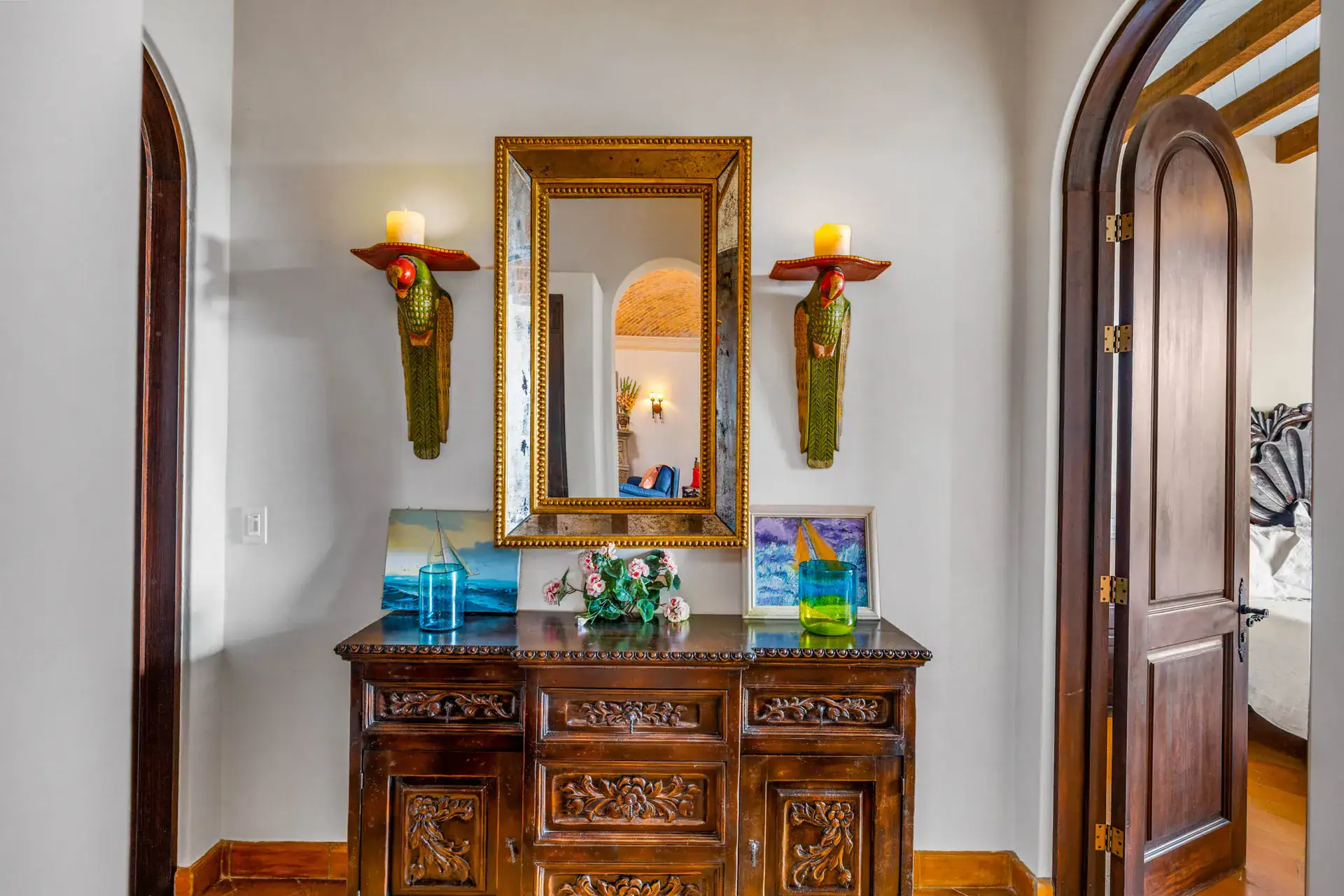 Casa Noche Magica, bedroom entry with a carved sideboard, a gold mirror and parrot candle sconces, San Miguel de Allende