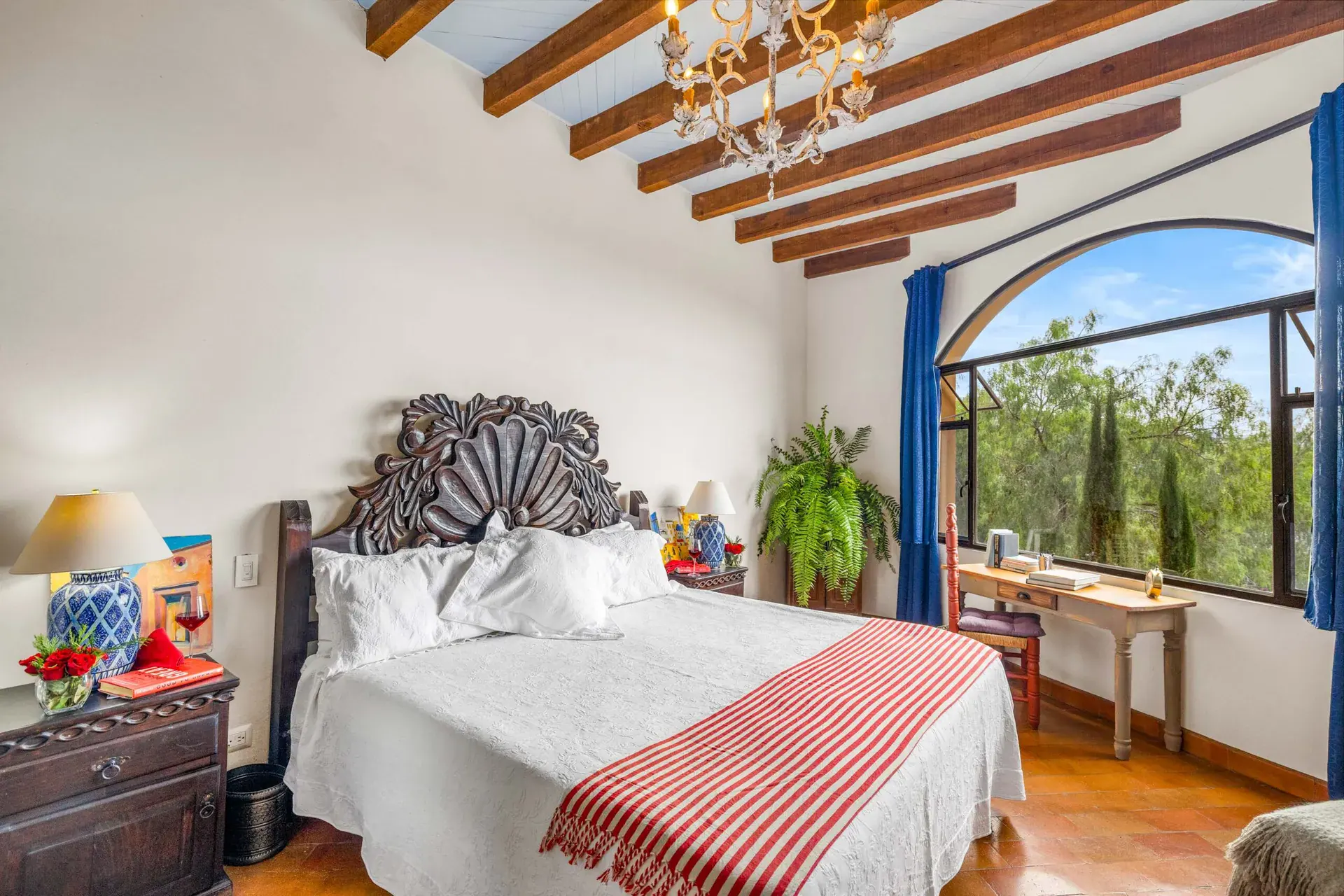 Casa Noche Magica, primary bedroom with a carved wood headboard, an arched picture window and a beamed ceiling, San Miguel de Allende