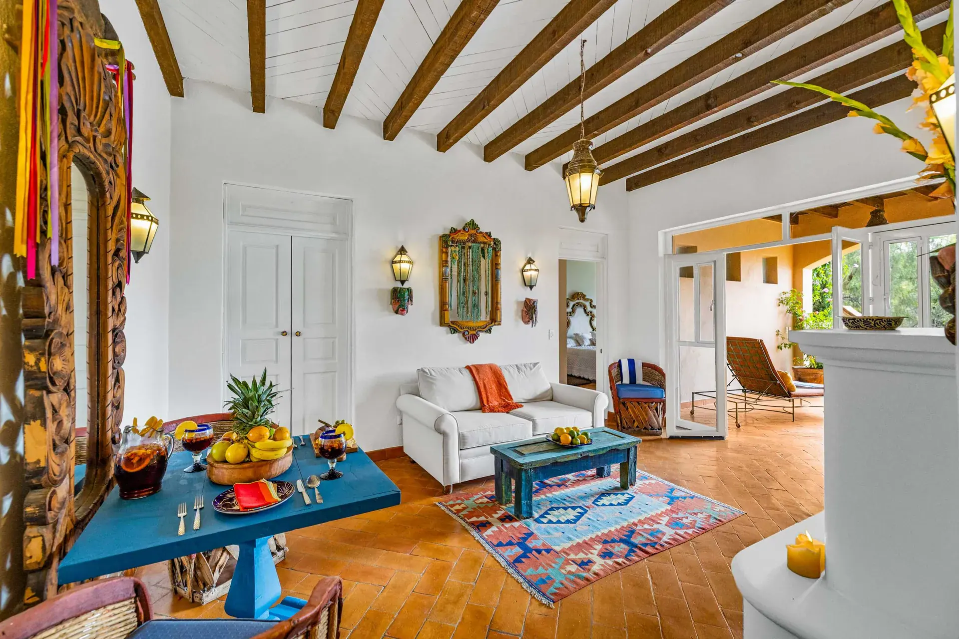 Casa Noche Magica, guest suite living room with a blue table with fruit, a white sofa, a fireplace and a colorful rug, San Miguel de Allende