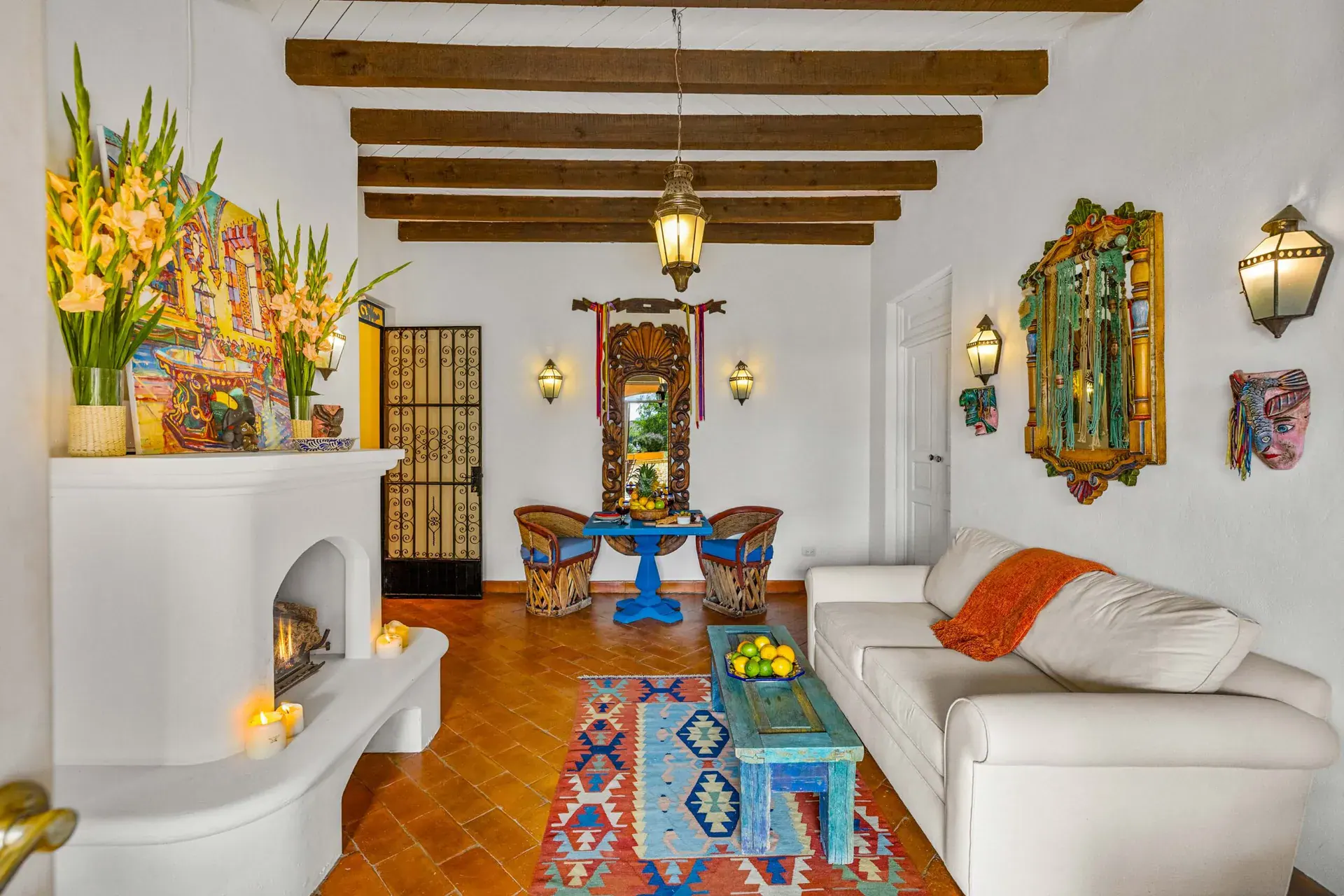Casa Noche Magica, guest suite living room with a white sofa, a fireplace with a painting and blue furniture, San Miguel de Allende