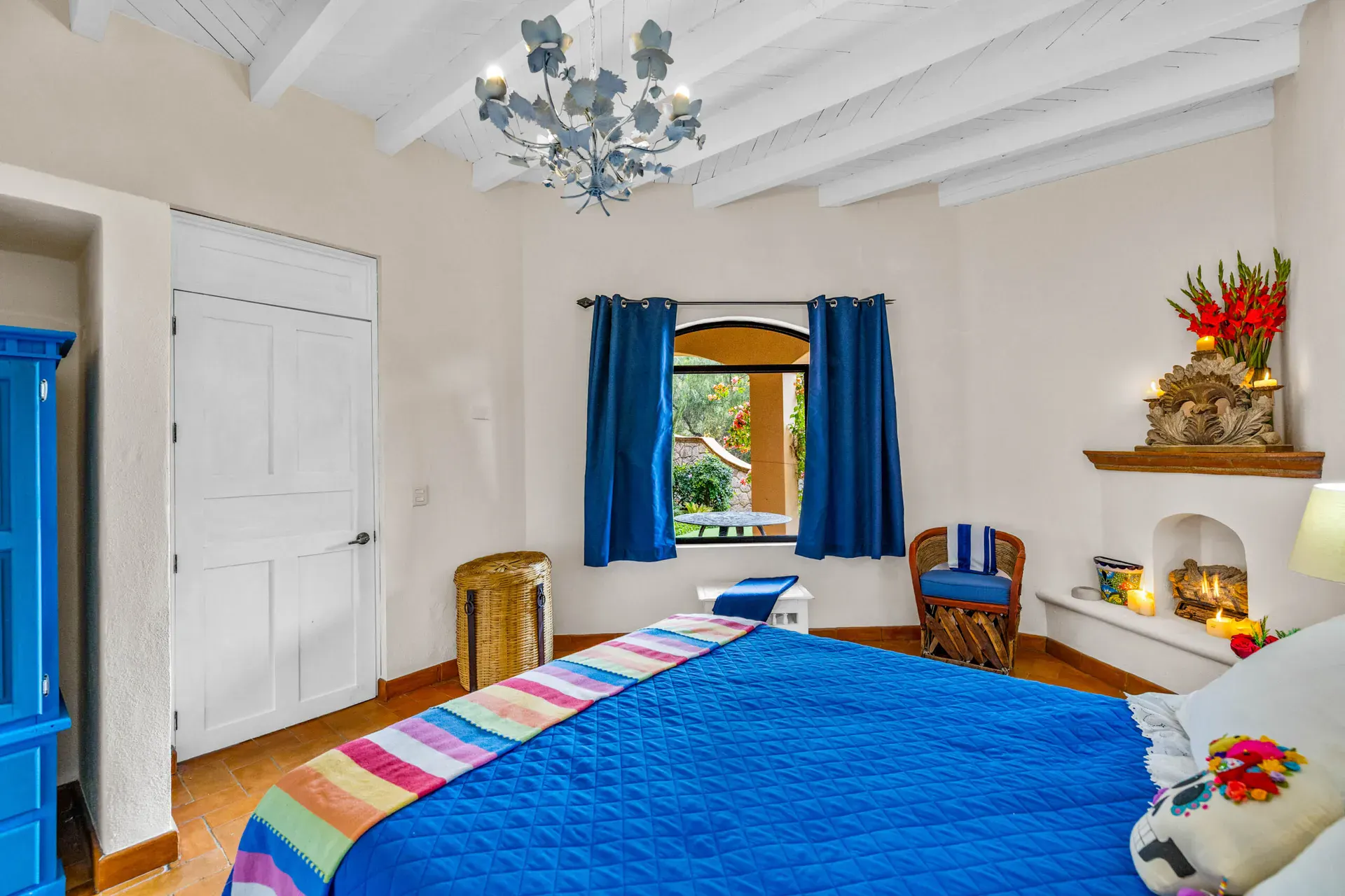 Casa Noche Magica, guest bedroom with a blue bed, a corner fireplace and white wardrobes, San Miguel de Allende