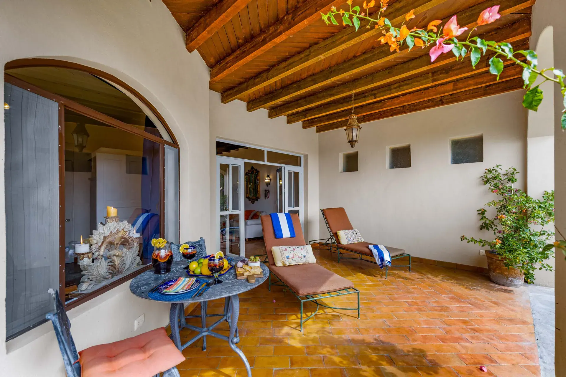 Casa Noche Magica, covered terrace with lounge chairs and a blue table beside arched openings to the suite, San Miguel de Allende
